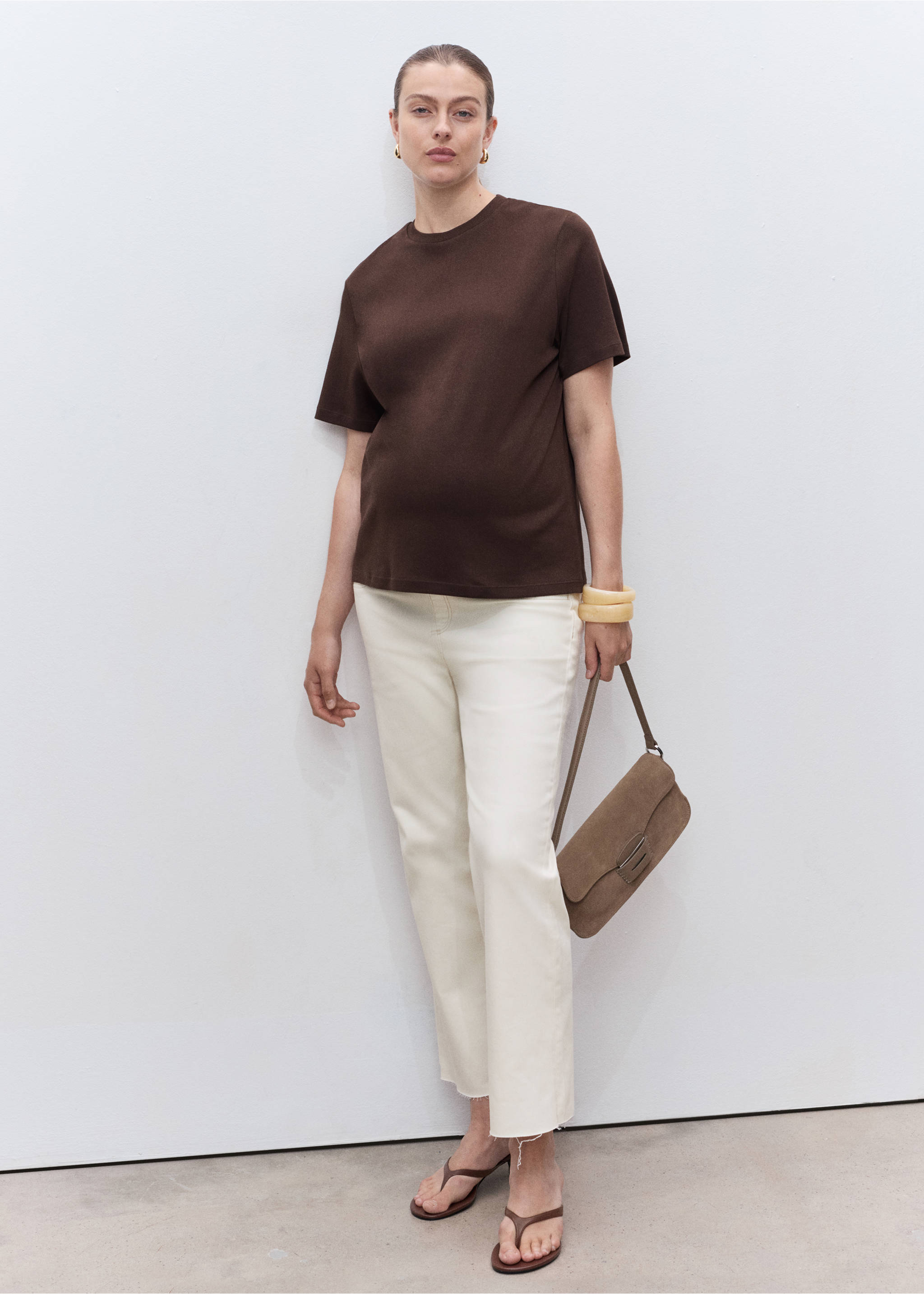 White trousers worn with a dark brown t-shirt and brown shoulder bag., Off White. Ref: 17001234-00.