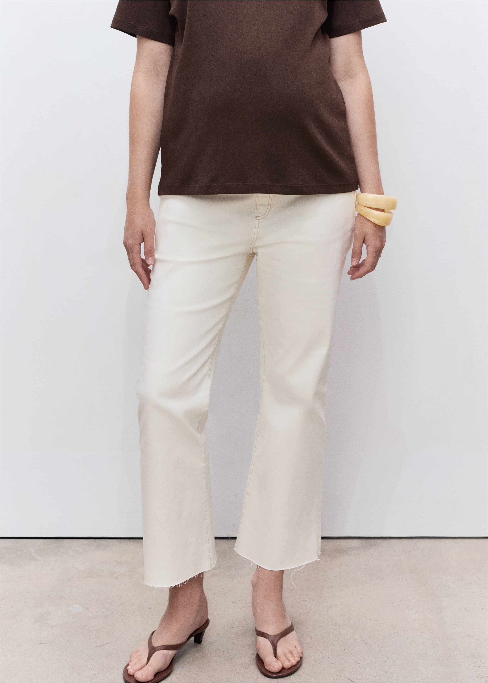 Cream denim trousers with raw-cut cropped hems, worn with a brown t-shirt and heeled sandals., Off White. Ref: 17001234-00.