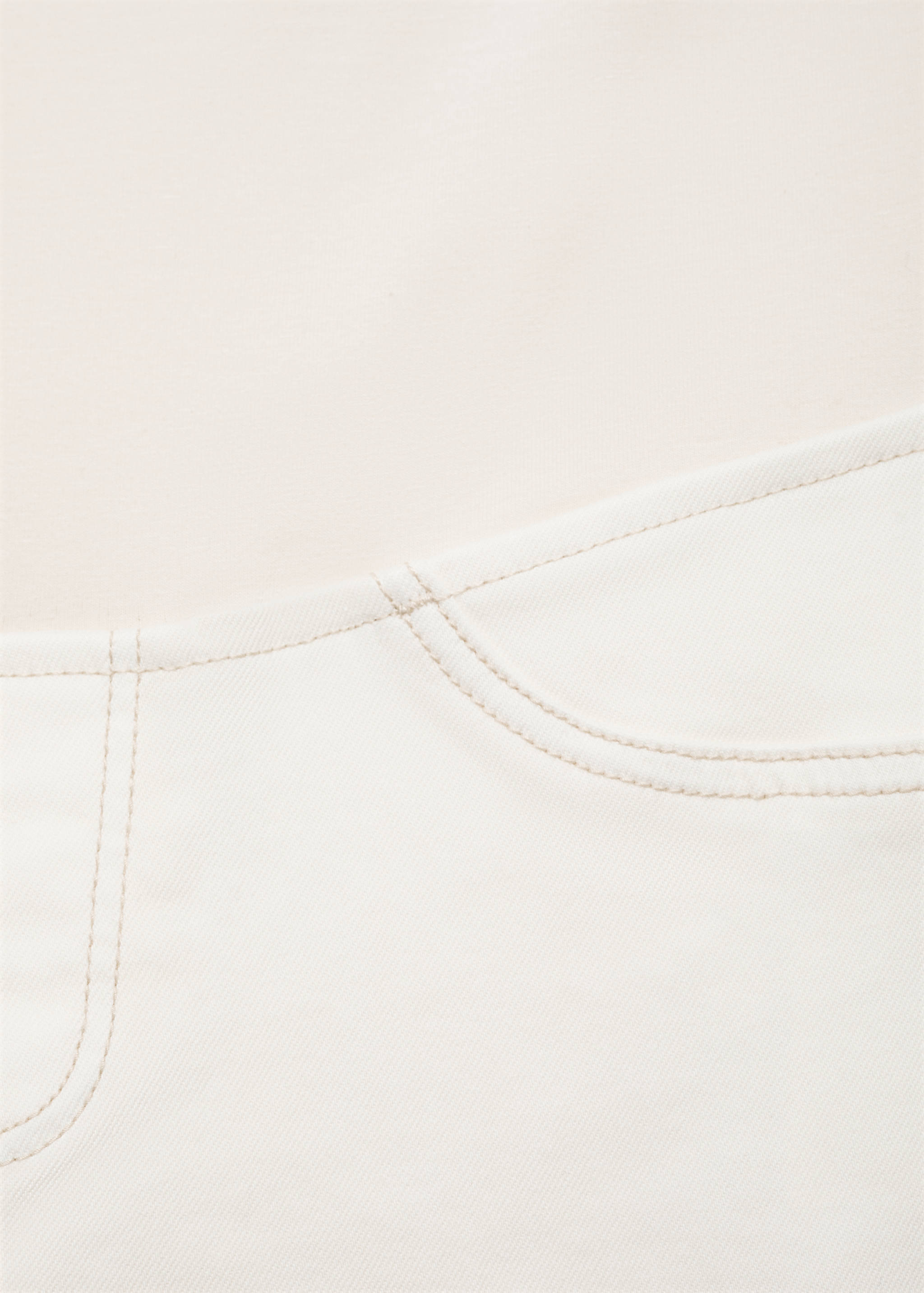 Close-up of white denim trousers showing front pocket detail.