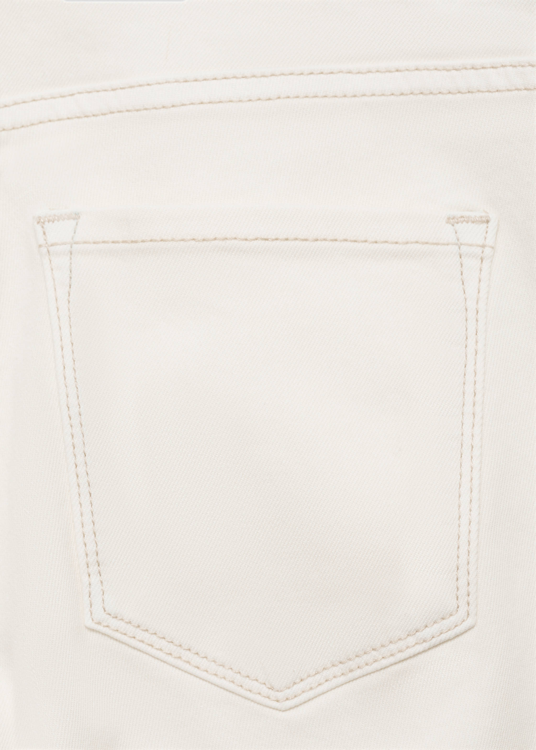 Close-up of light beige denim trousers fabric and back pocket.
