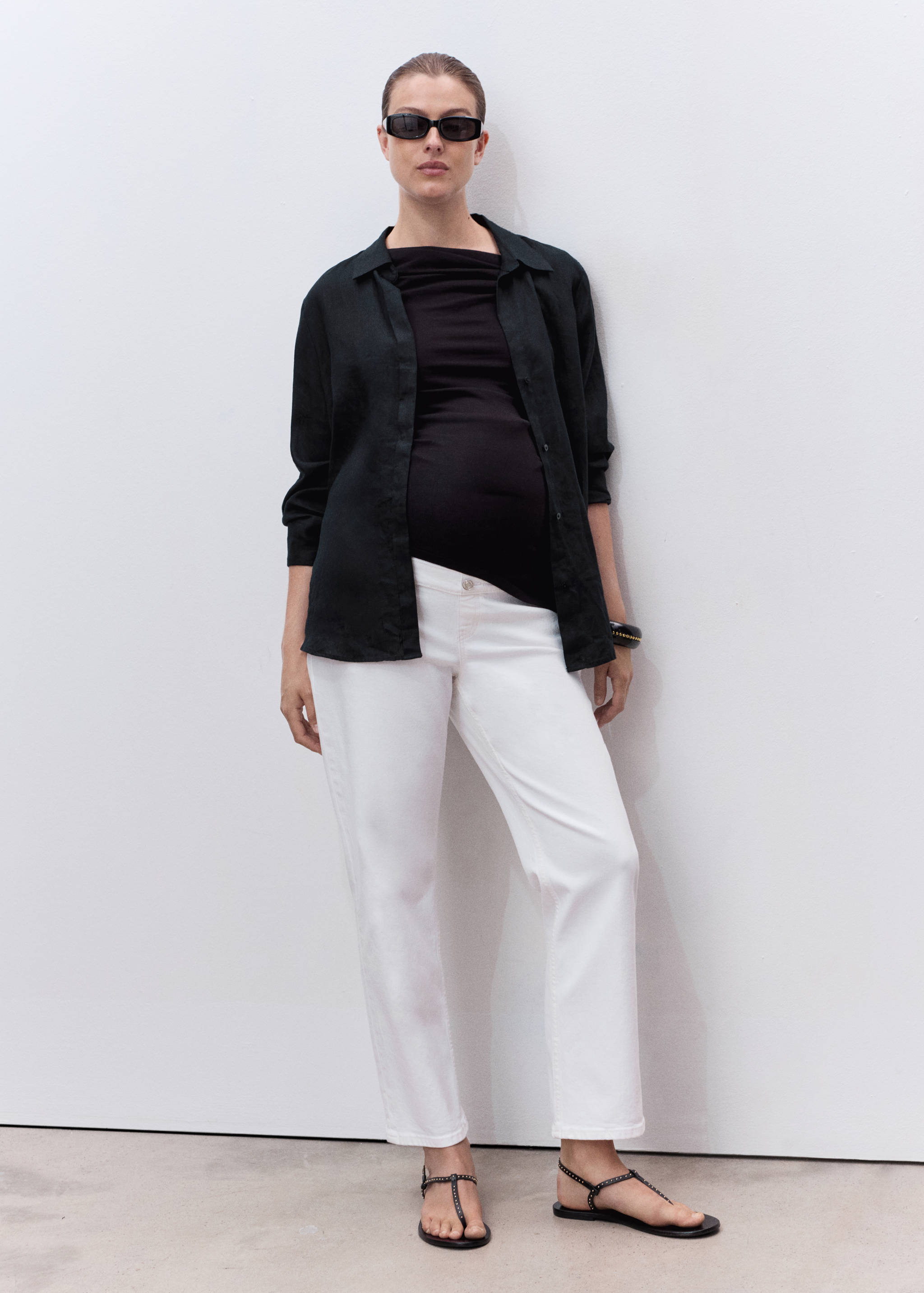 White straight-leg denim trousers worn with an unbuttoned black overshirt