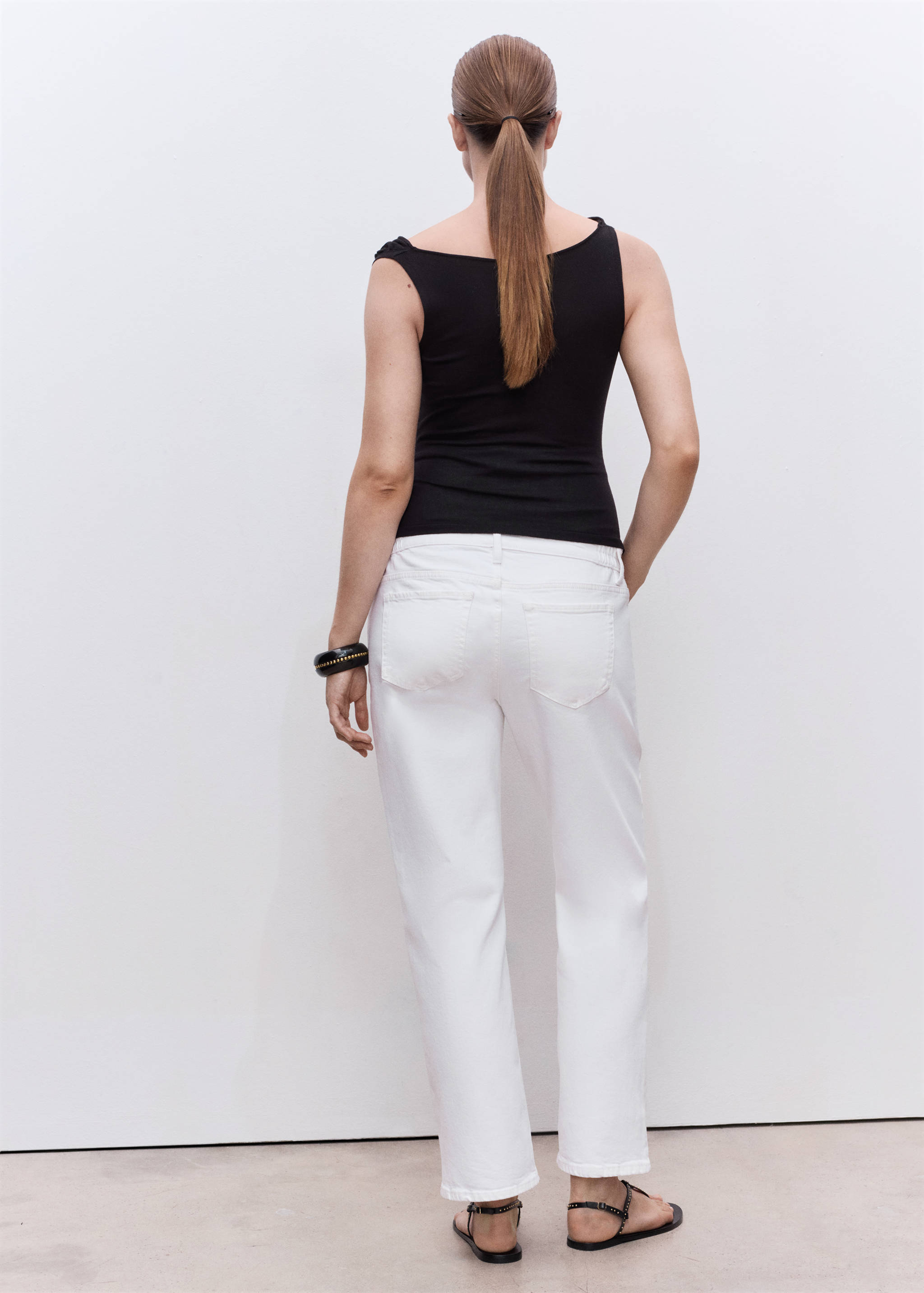 Back view of white denim trousers paired with a black top.