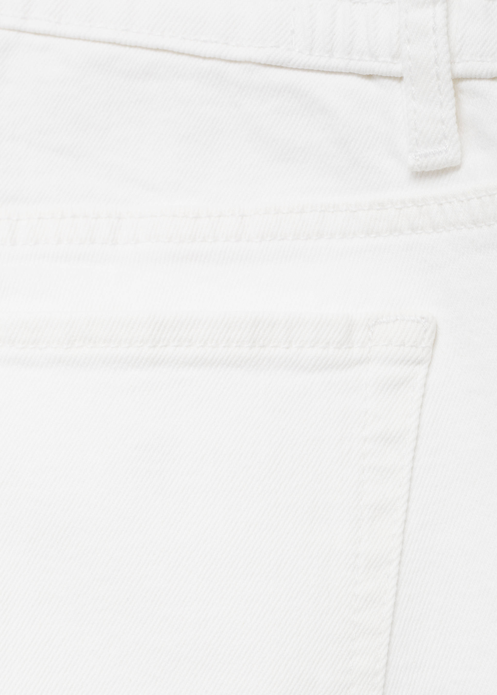 Close-up of white denim trousers showing fabric texture and back pocket detail.