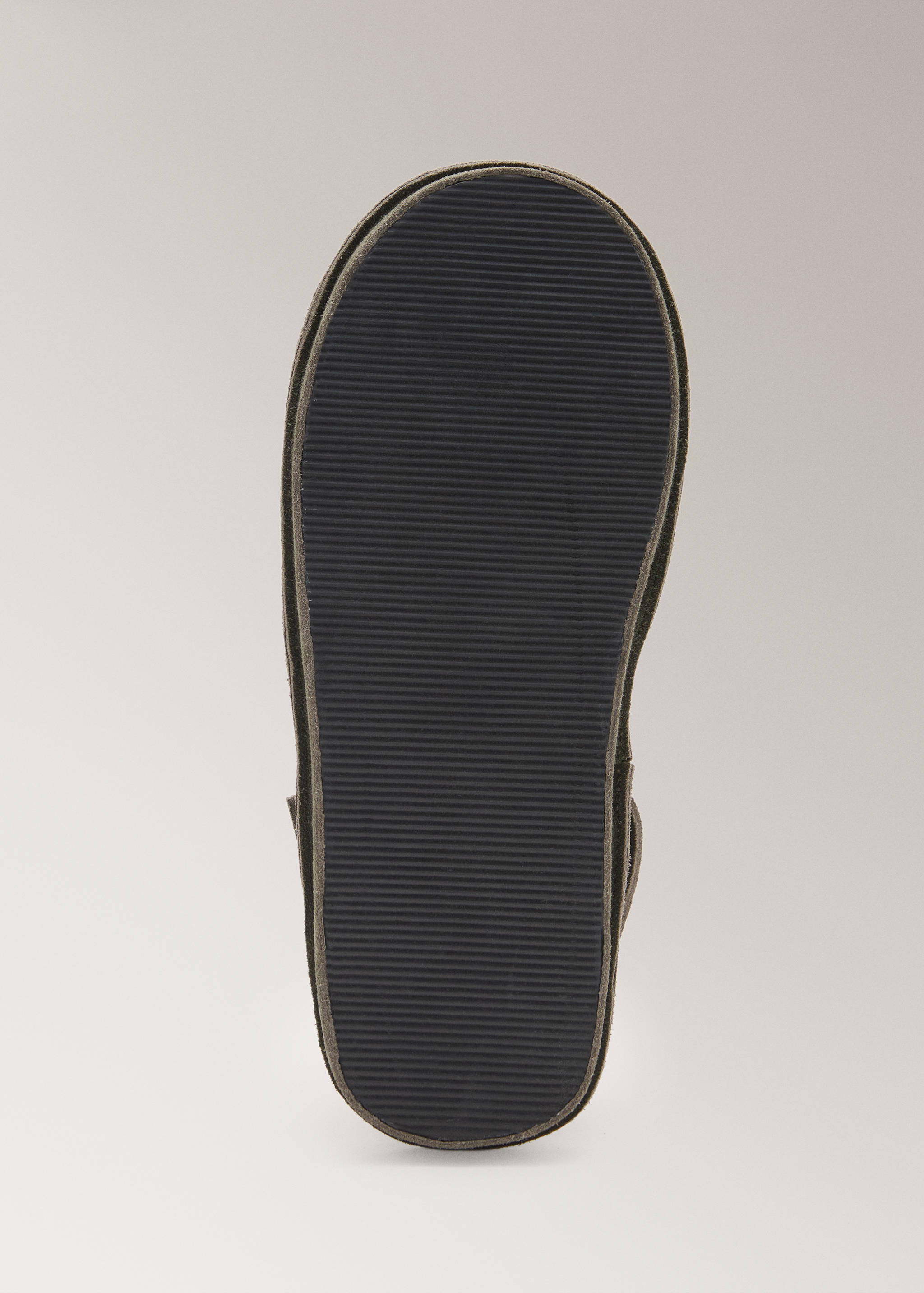 Close-up of the ribbed rubber sole of a dark grey slipper.