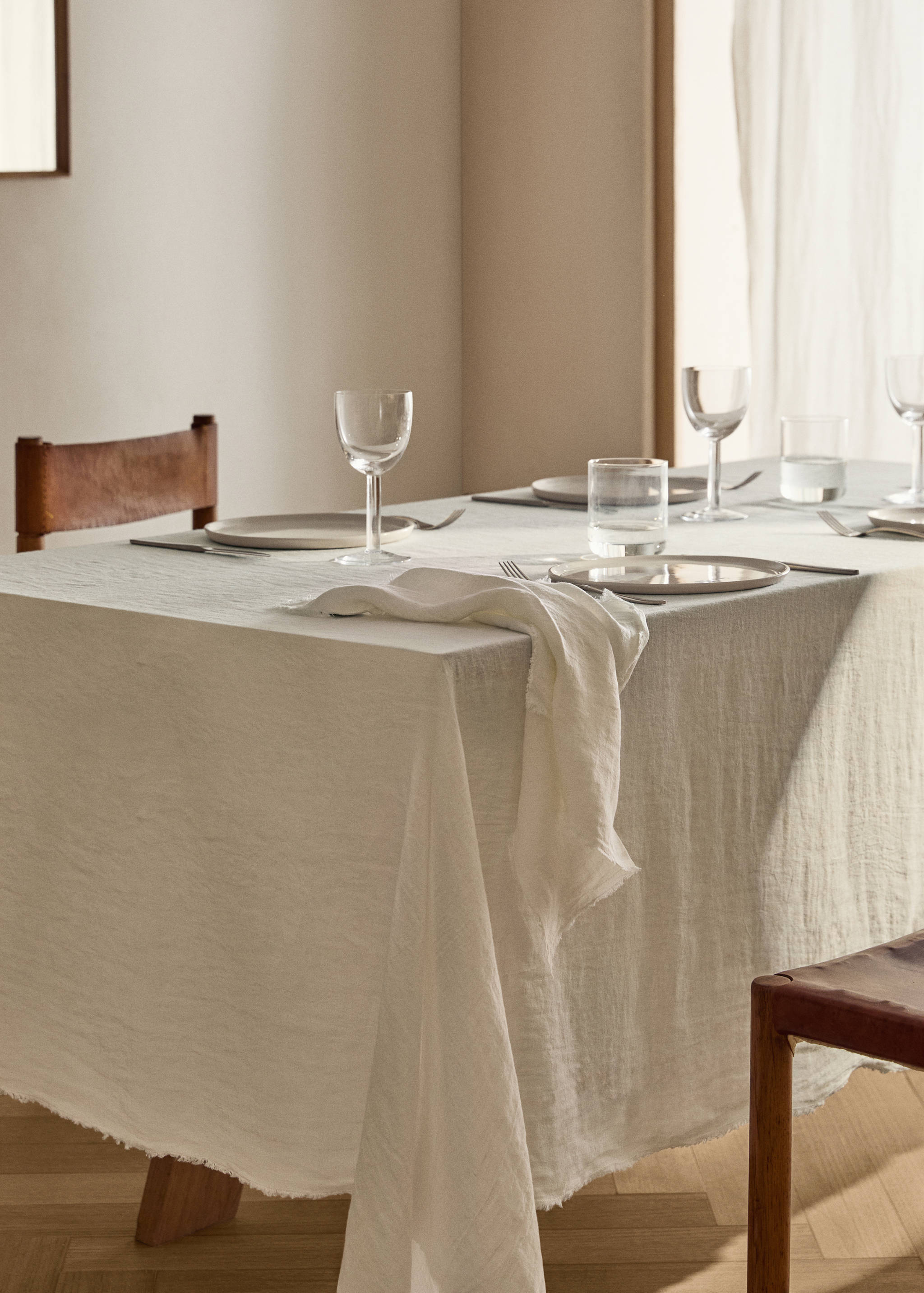 Cream tablecloth with frayed edges on a set dining table.