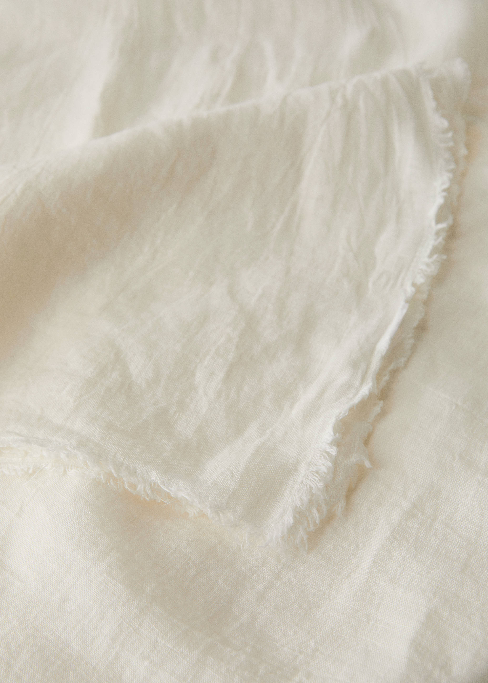 Off-white tablecloth detail with raw frayed edges.