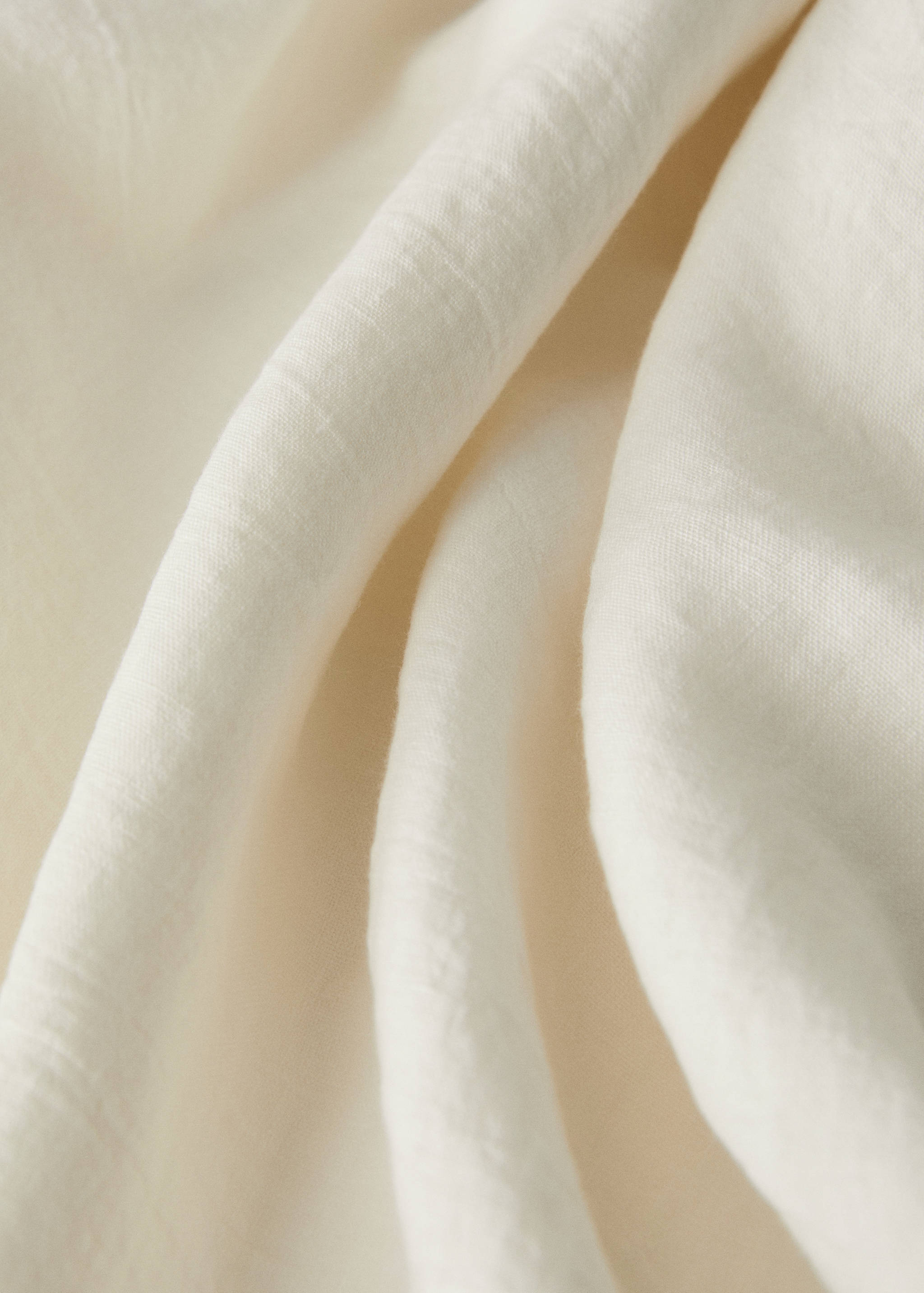 Close-up of an off-white tablecloth showing the textured fabric detail.