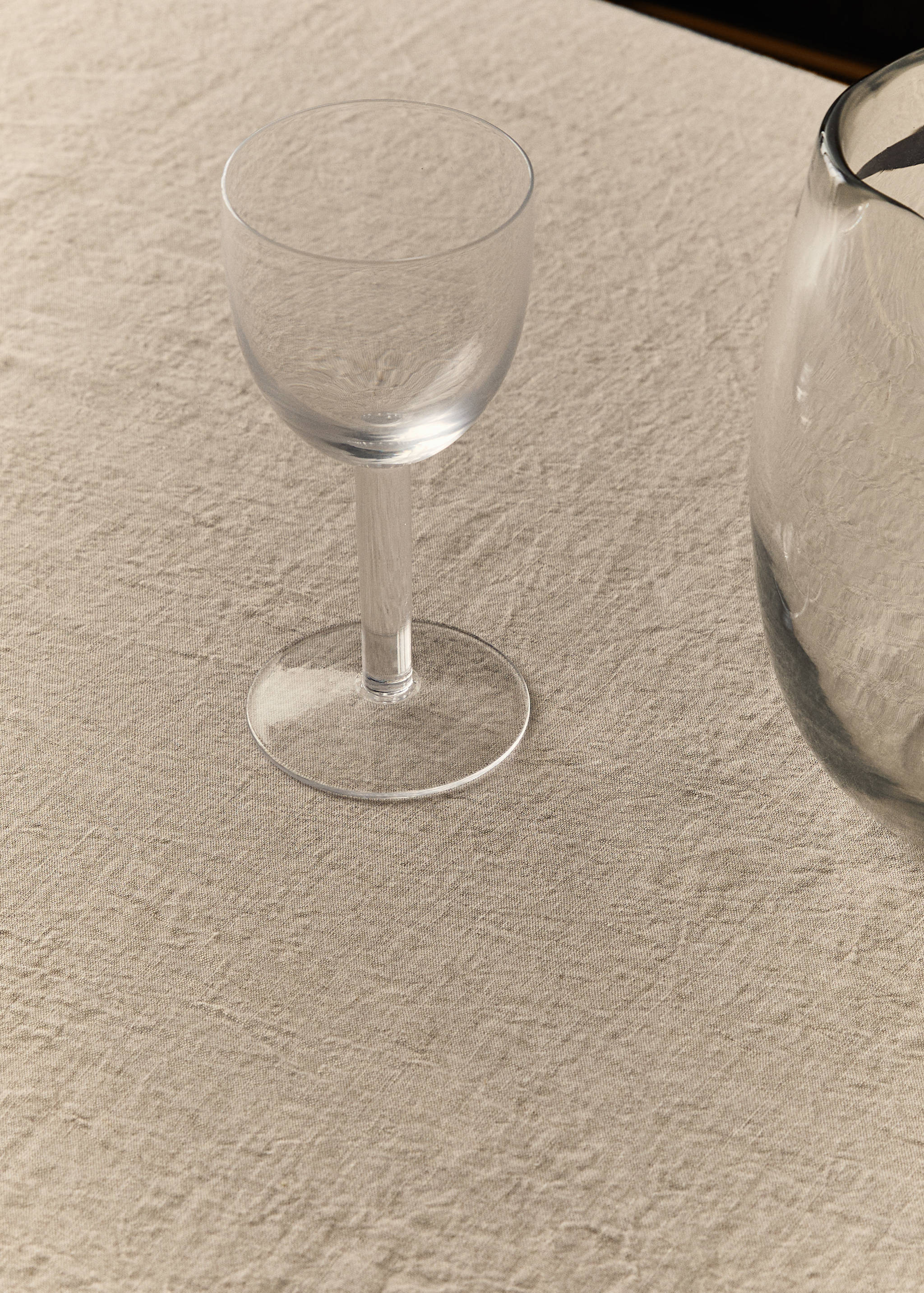 Light beige textured tablecloth styled with a clear glass goblet.