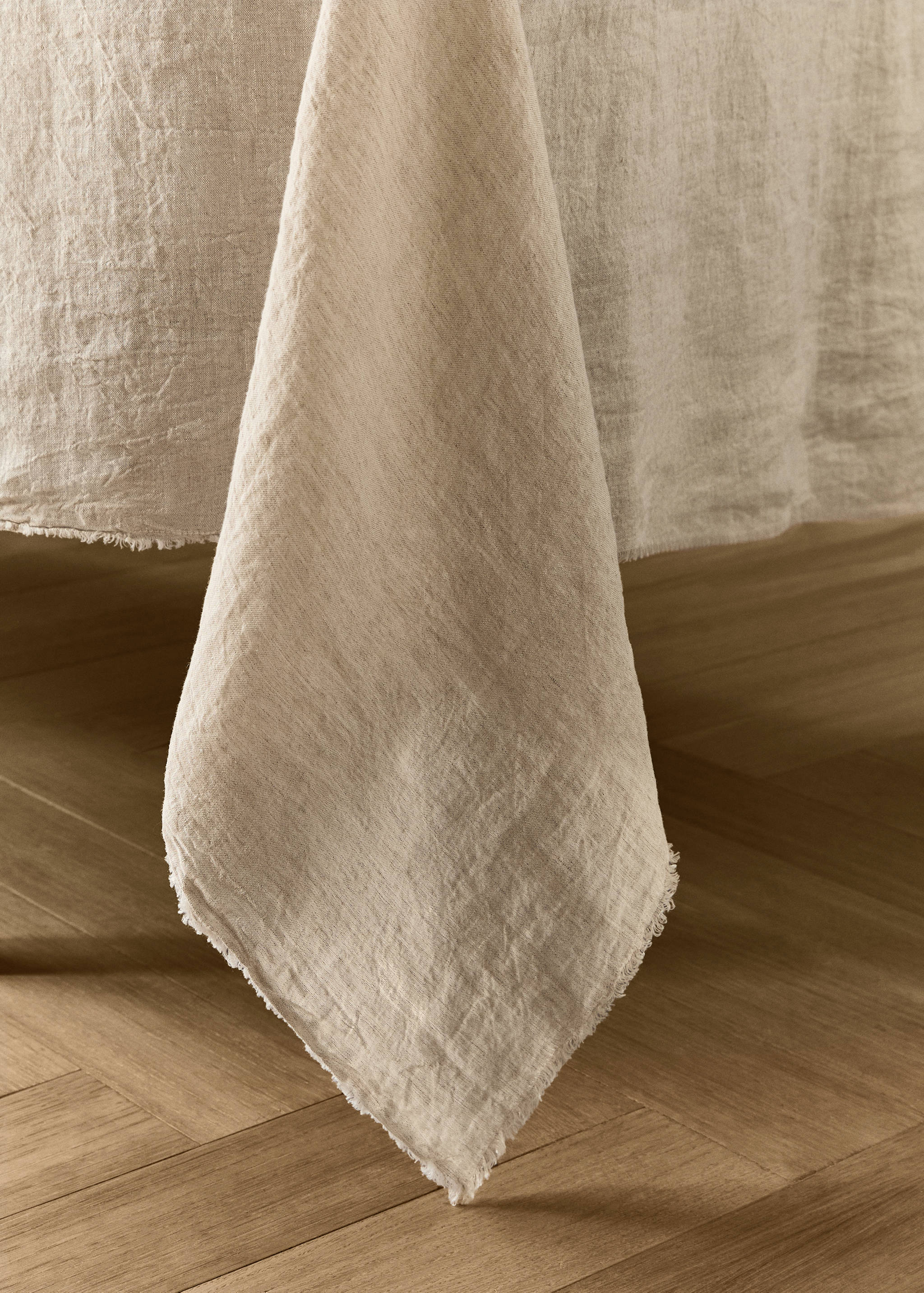 Beige textured tablecloth with frayed edges.