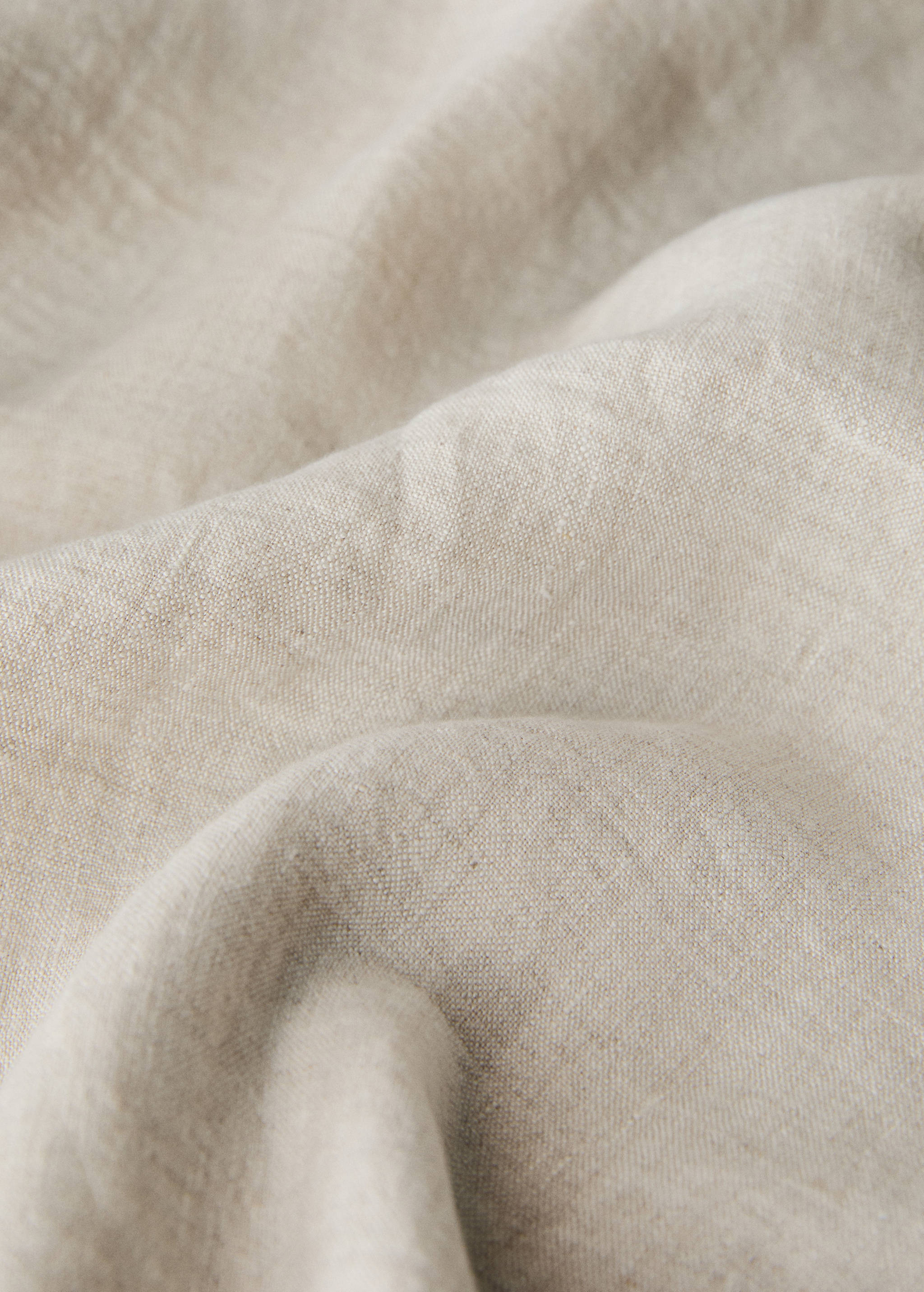 Close-up of a beige tablecloth showing its textured, woven fabric.