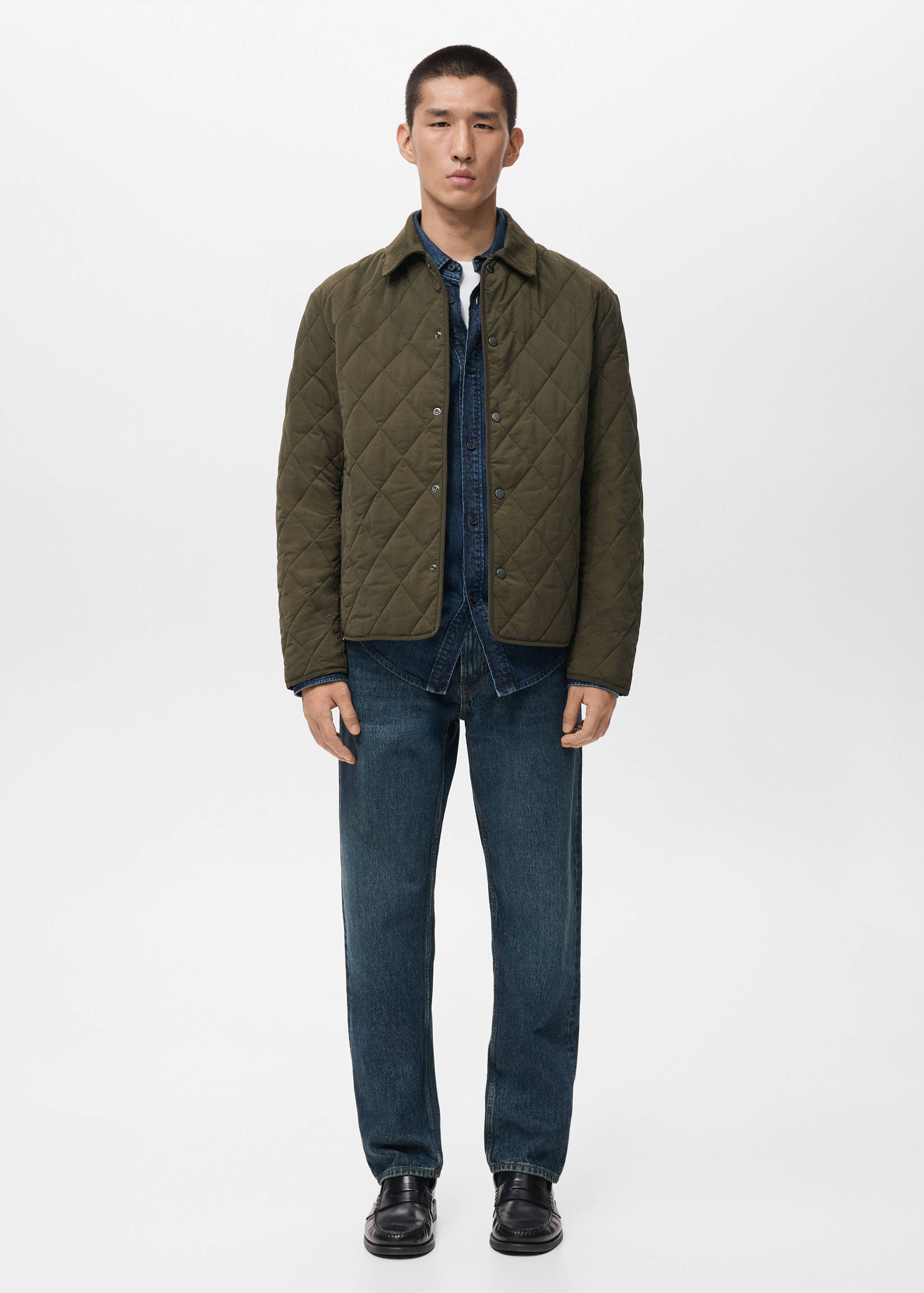 Olive green quilted jacket with snap buttons, worn over a denim shirt and trousers.