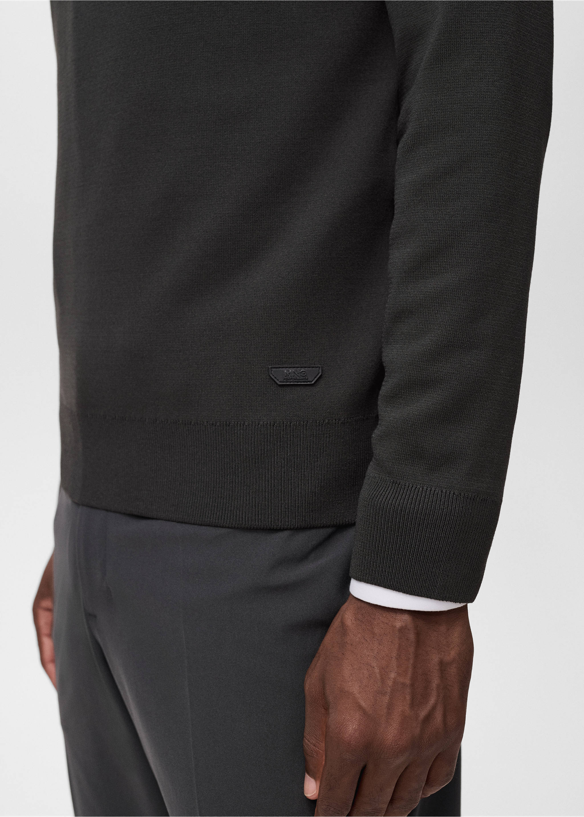 Close-up of a dark green knitted jersey with a small logo badge., Dark Green. Ref: 17005979-00.