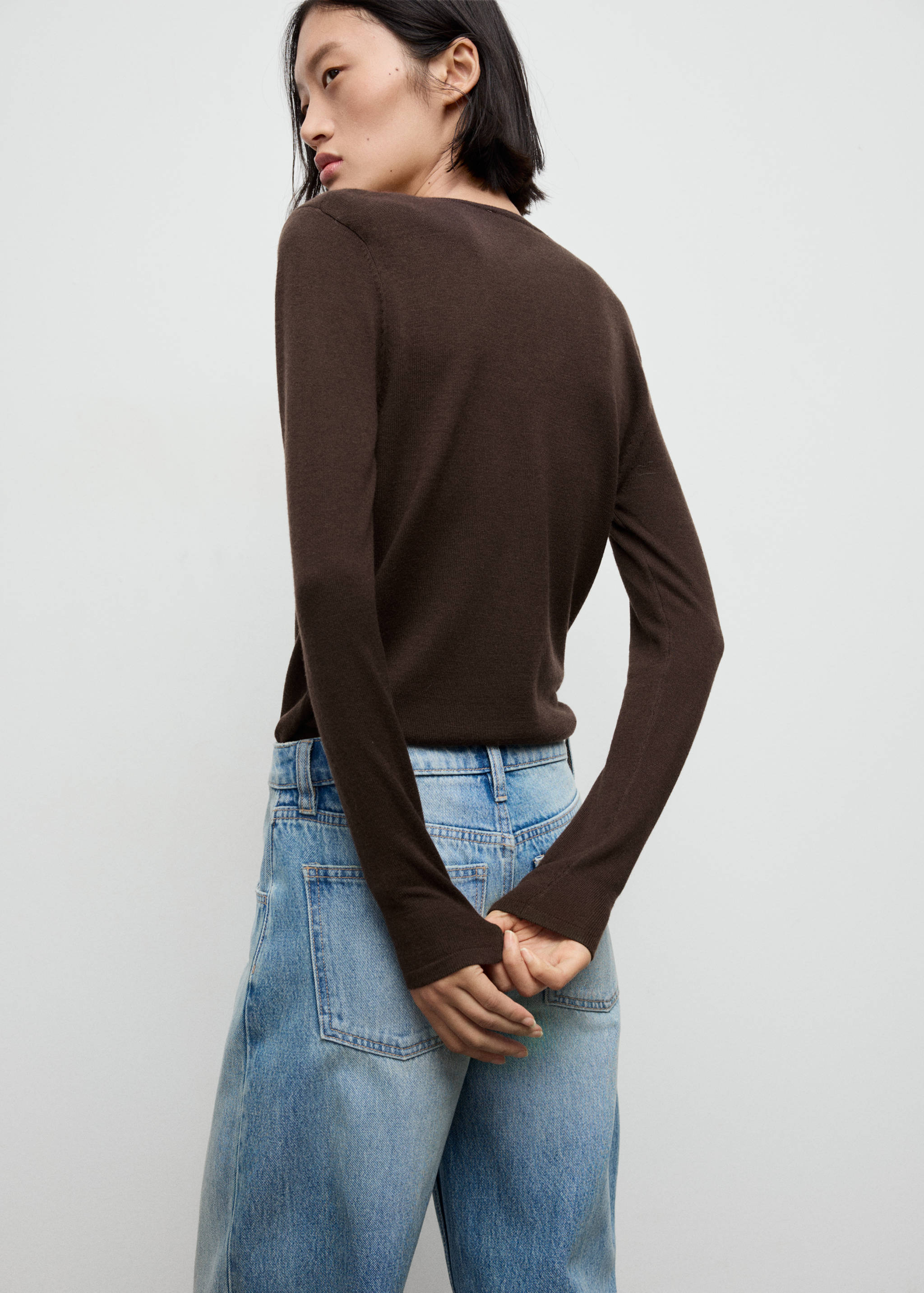 Brown long-sleeved jersey seen from the back, paired with light blue trousers.