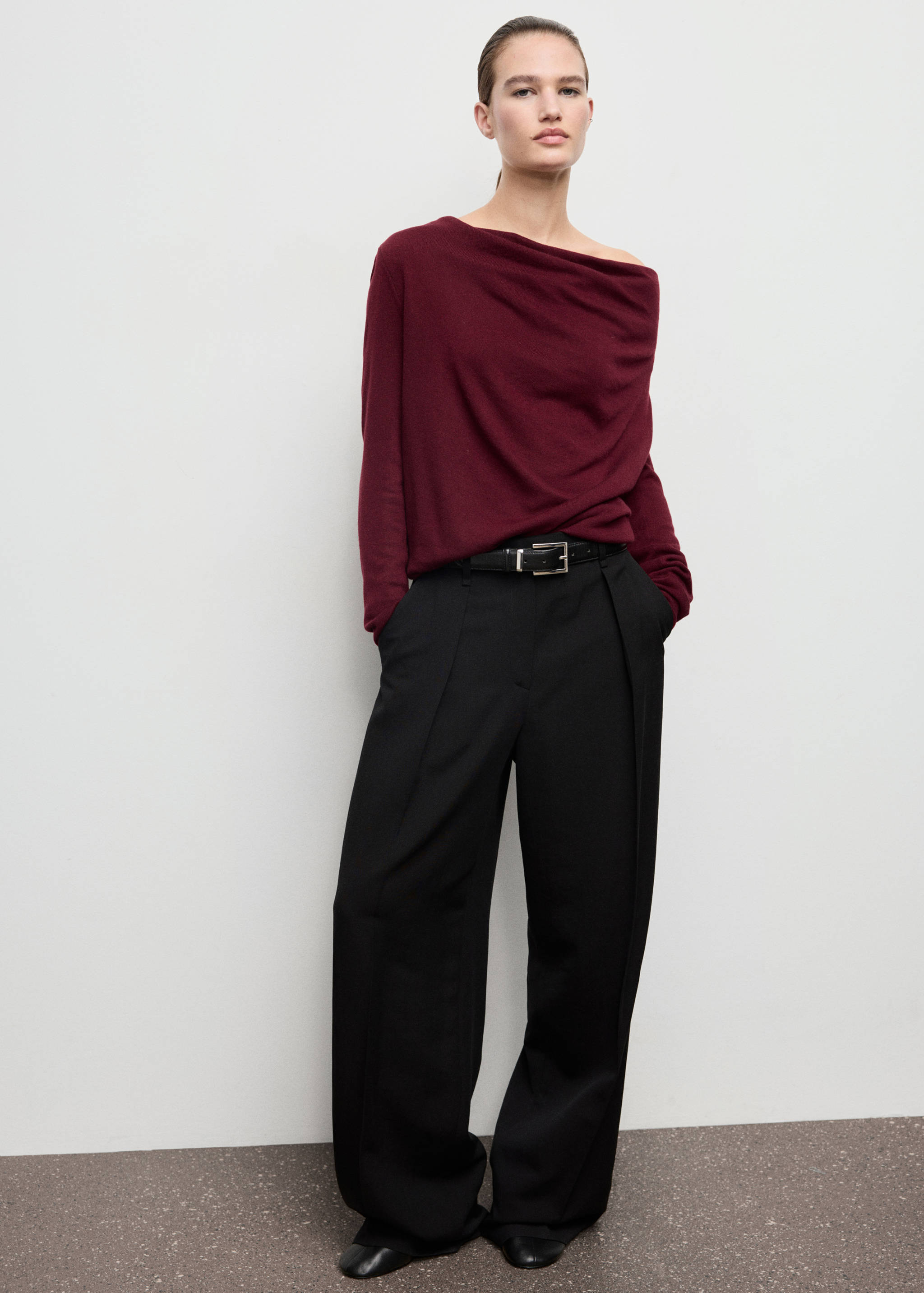 Burgundy jersey with draped asymmetric neckline, worn with black trousers.