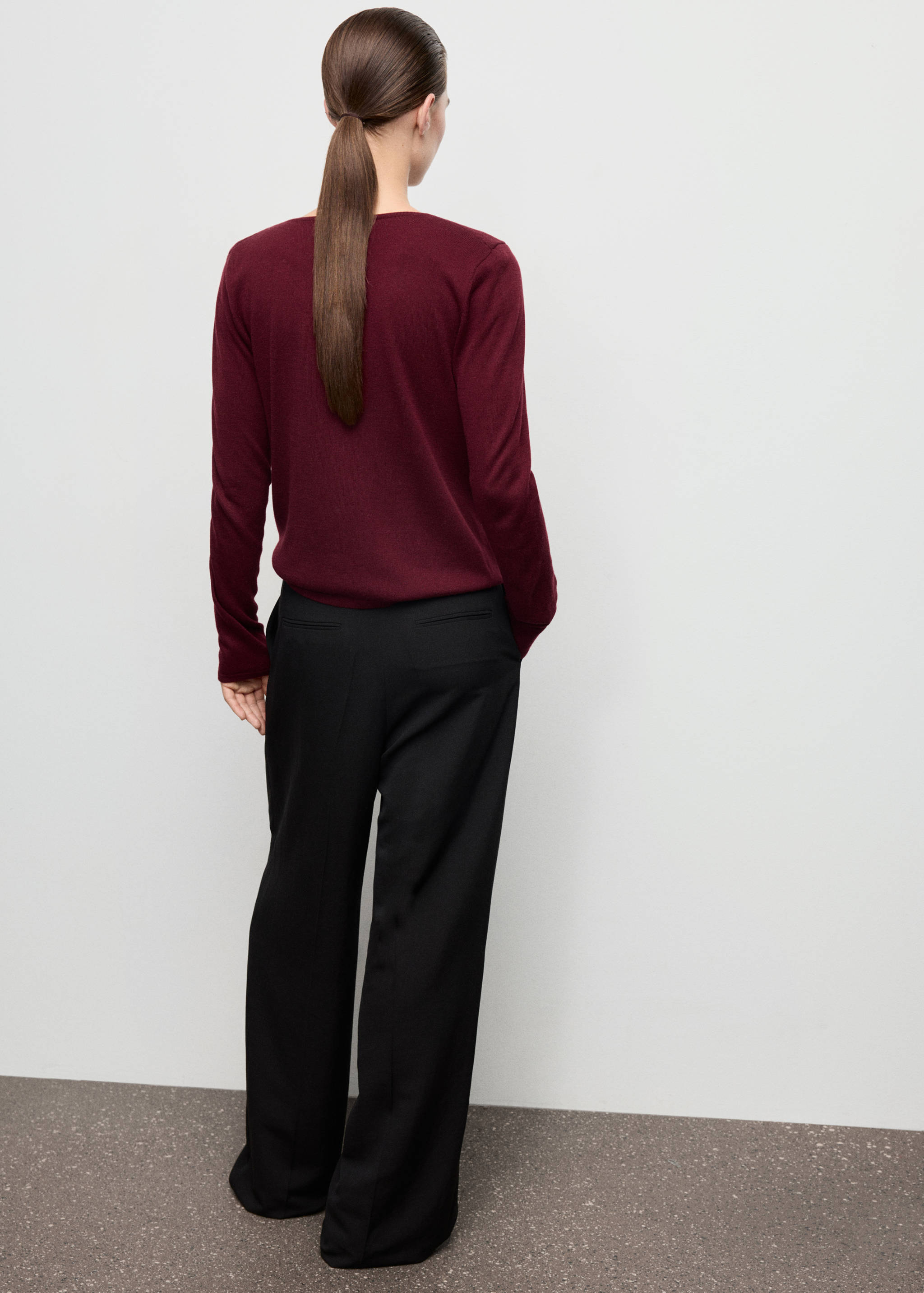 Burgundy jersey seen from the back, paired with black trousers.