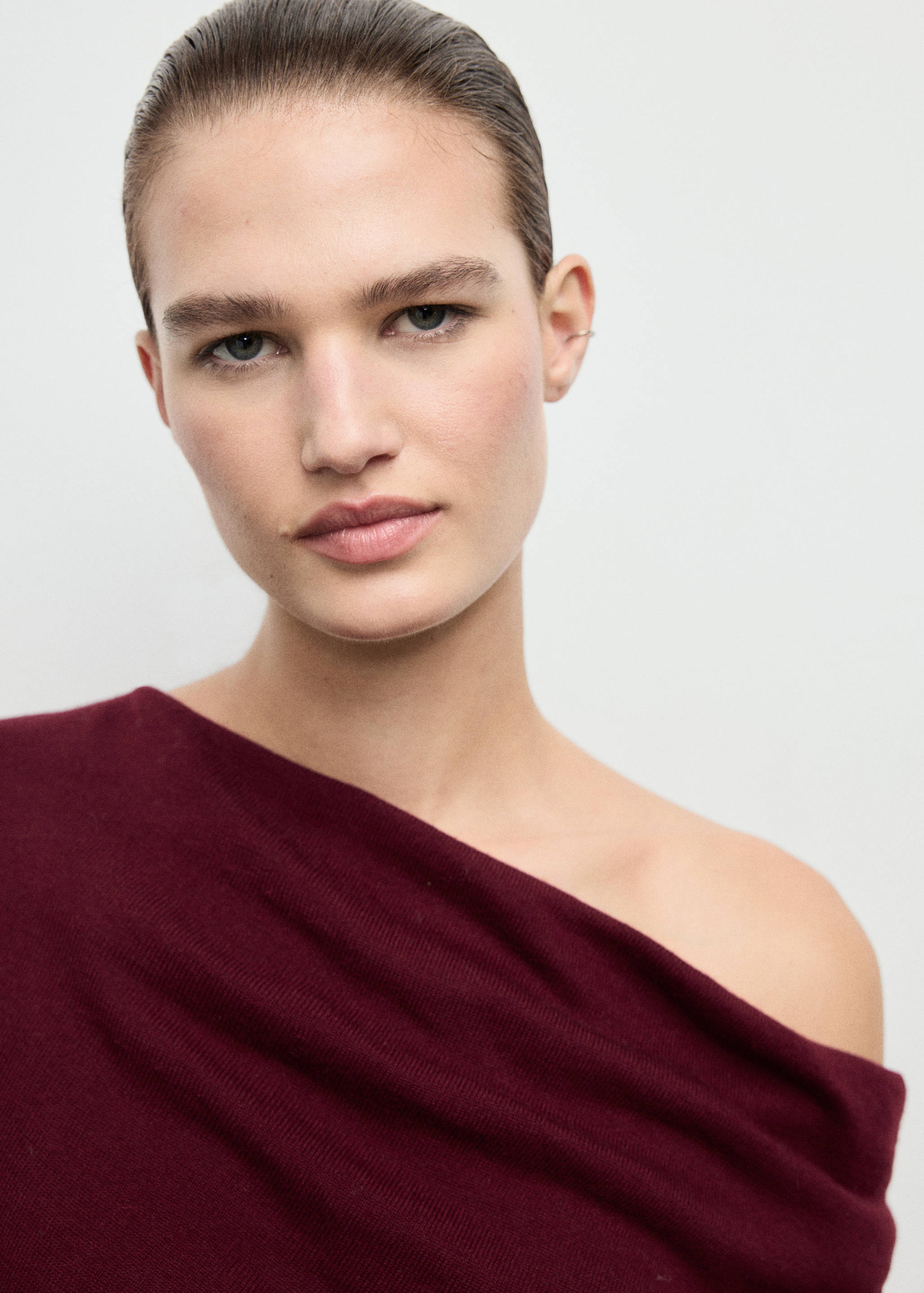 Burgundy jersey with an asymmetric off-the-shoulder neckline.