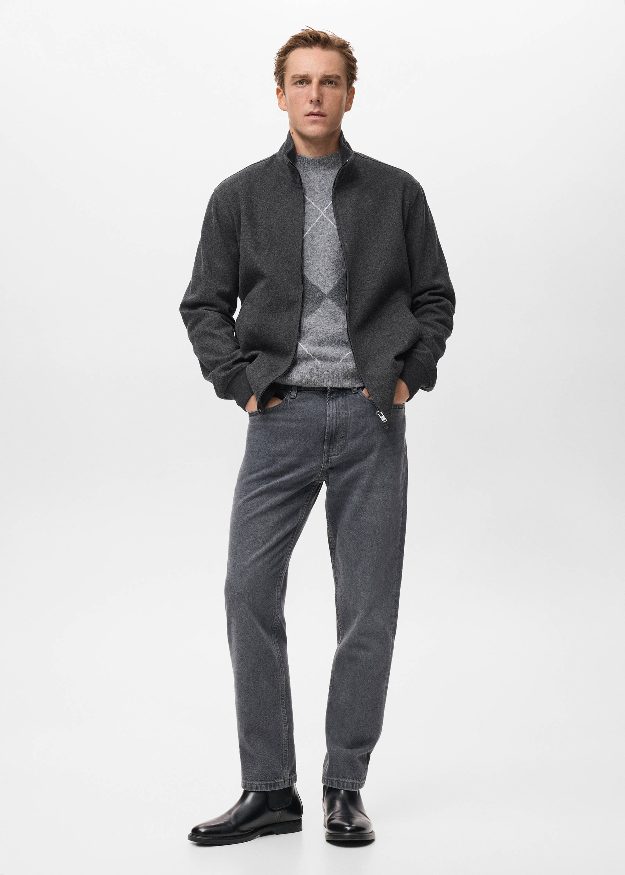 Dark grey zip-up sweatshirt worn with an argyle sweater, grey trousers and black boots.