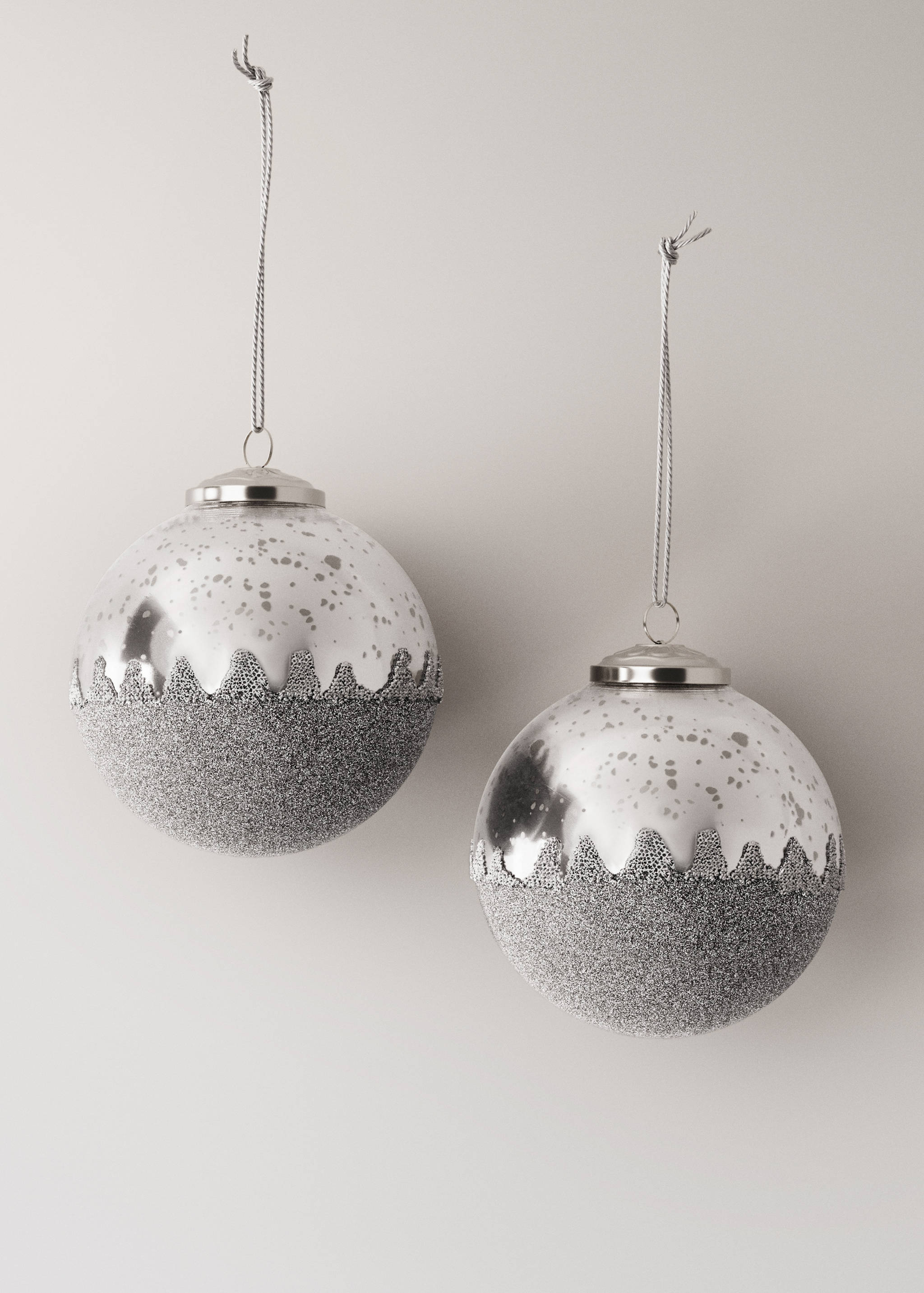 Two silver Christmas ornaments with speckled and glittery lower halves.