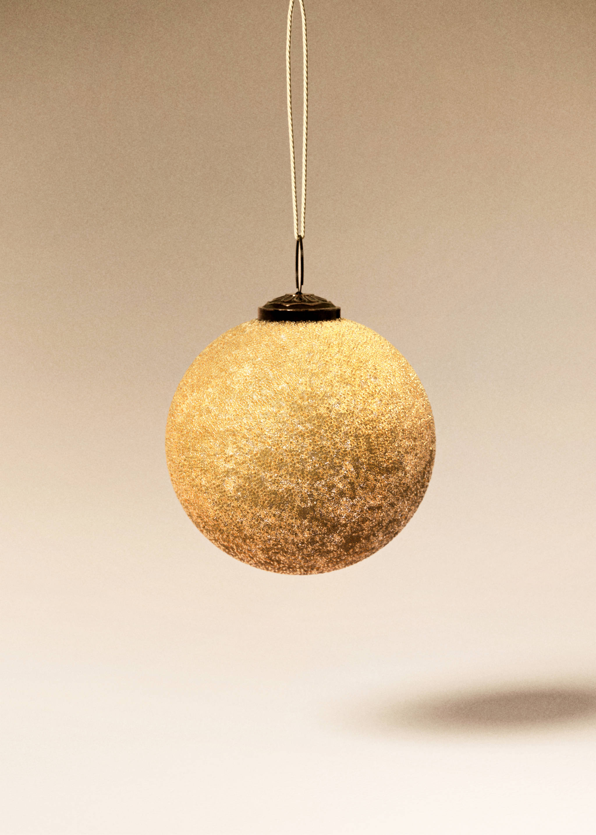 Textured gold spherical Christmas ornament with a hanging cord.