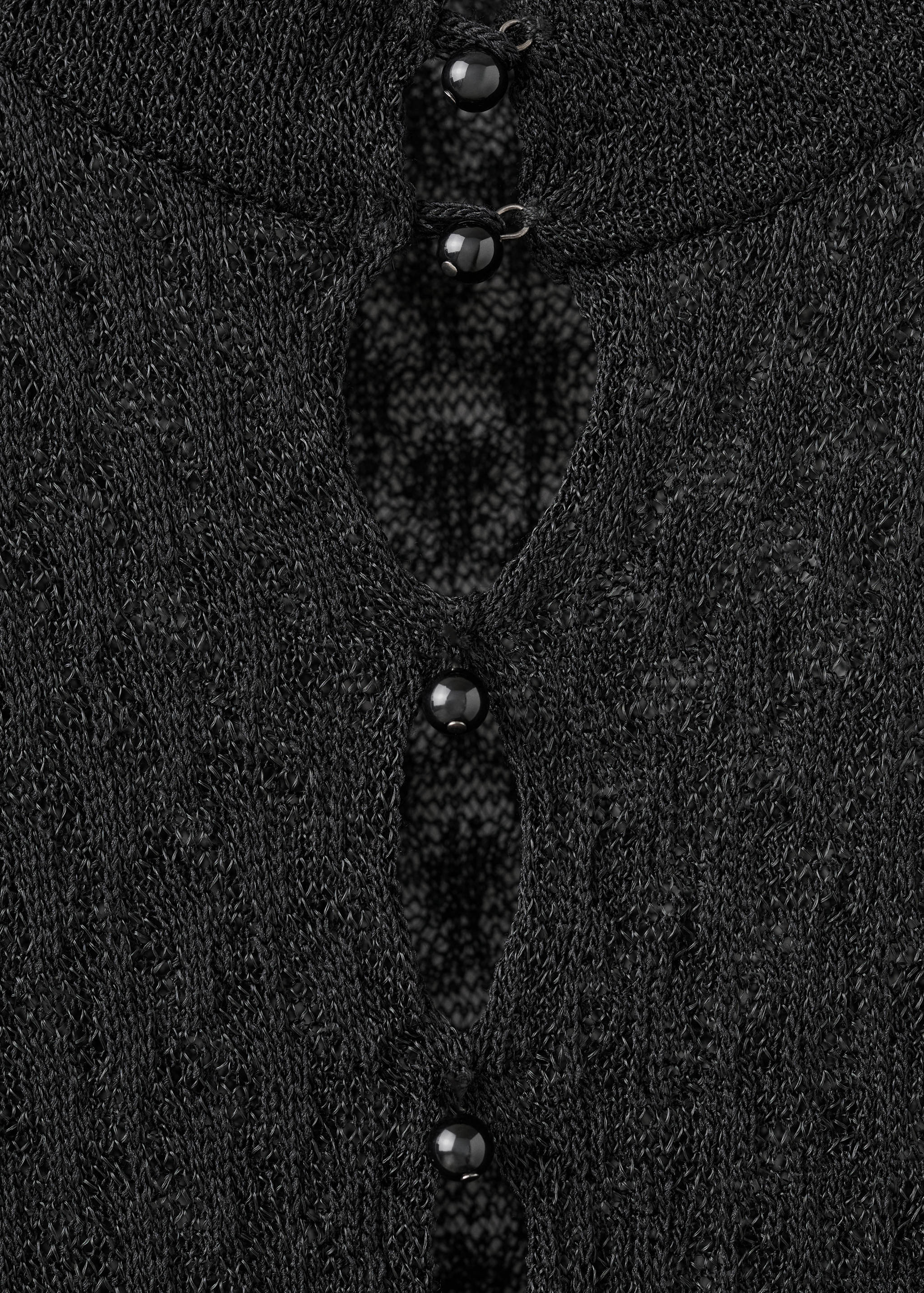 Black knit jersey fabric detail showing round buttons and keyholes.
