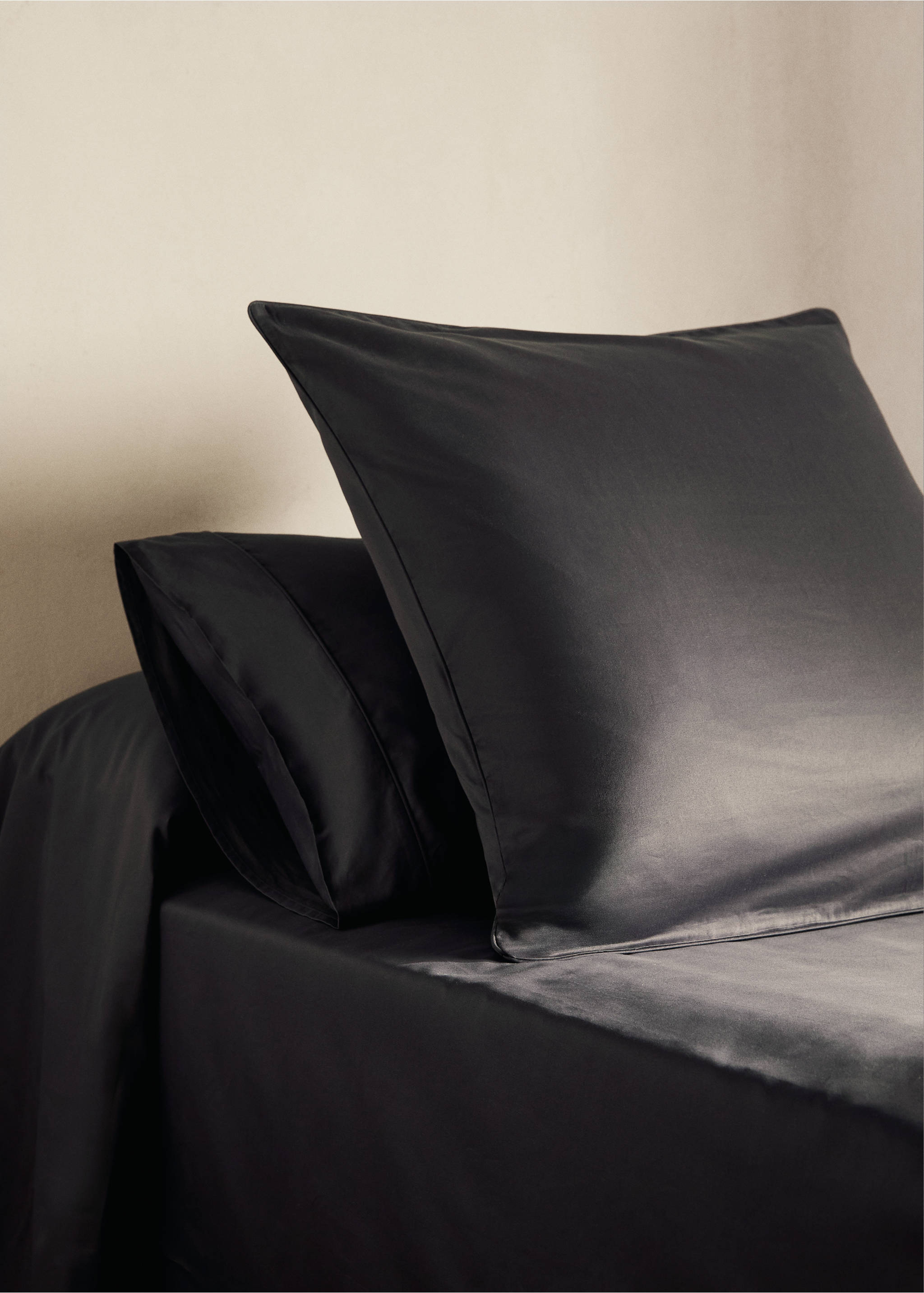 Dark grey silky pillowcase with a stitched border on a made bed., Dark Grey. Ref: 17011583-00.