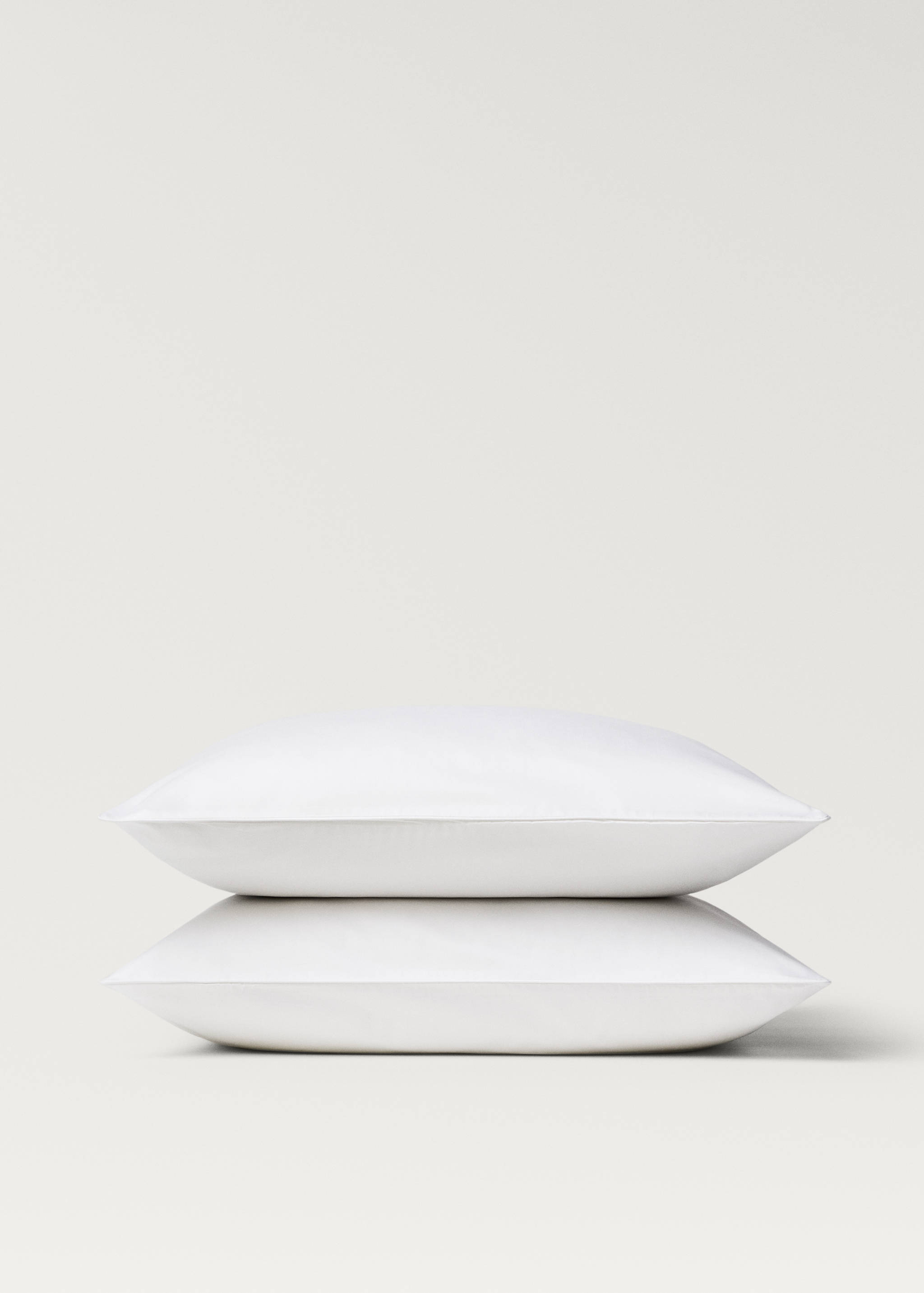 Plain white pillowcases stack in a close-up studio view.