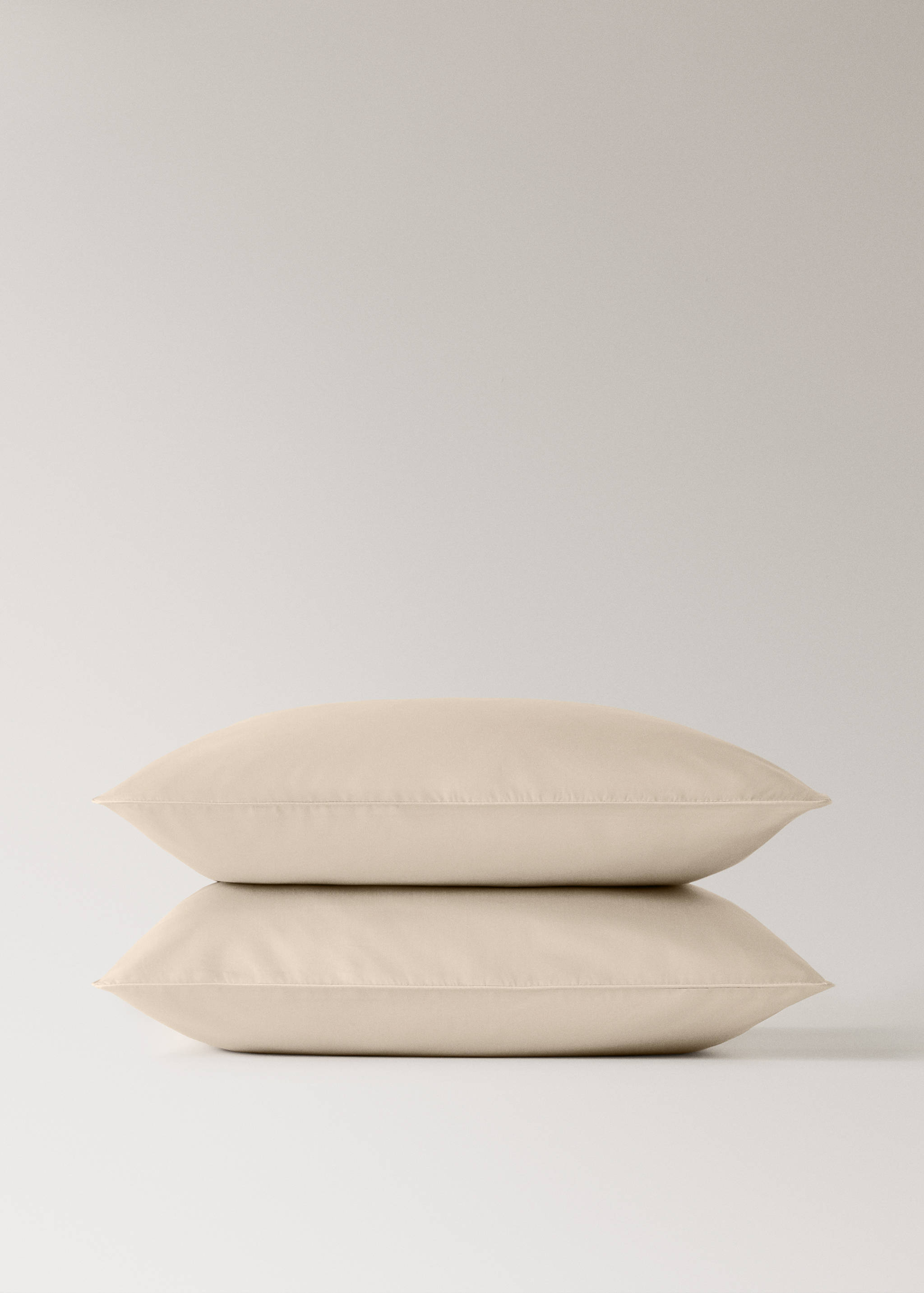 Two solid beige pillowcases stacked against a plain background.