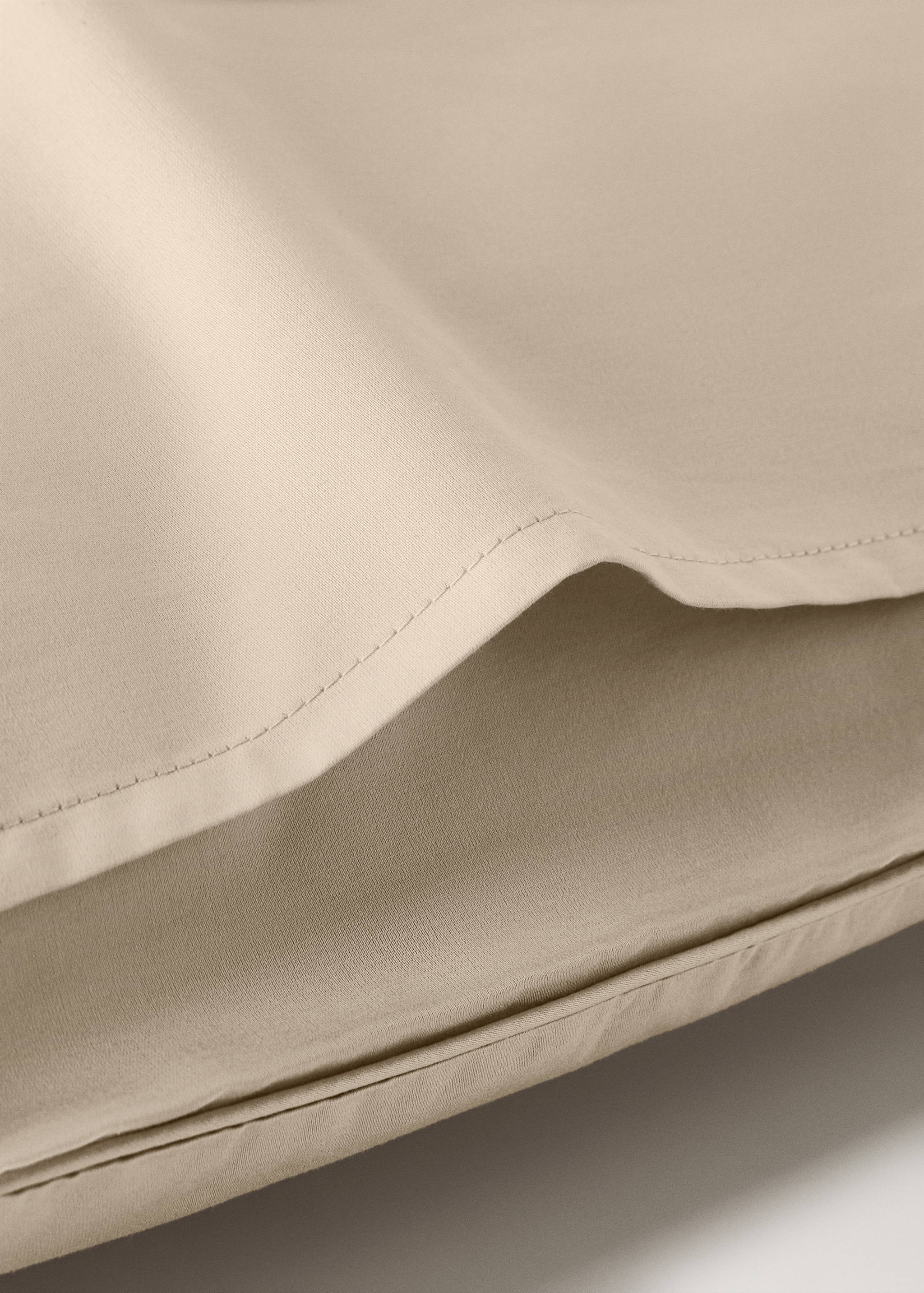 Beige pillowcase detail showing stitched edge.