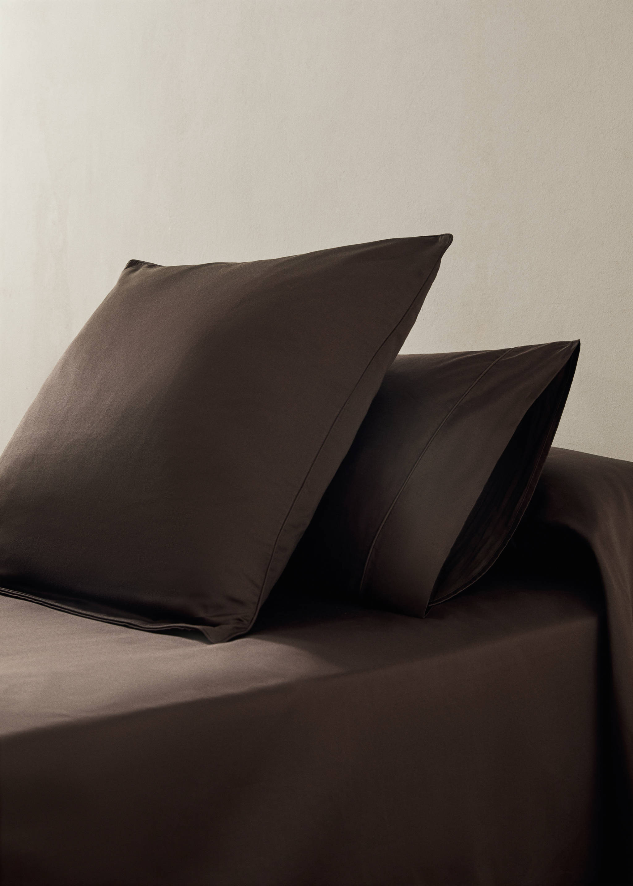 Dark brown pillowcases on a bed.