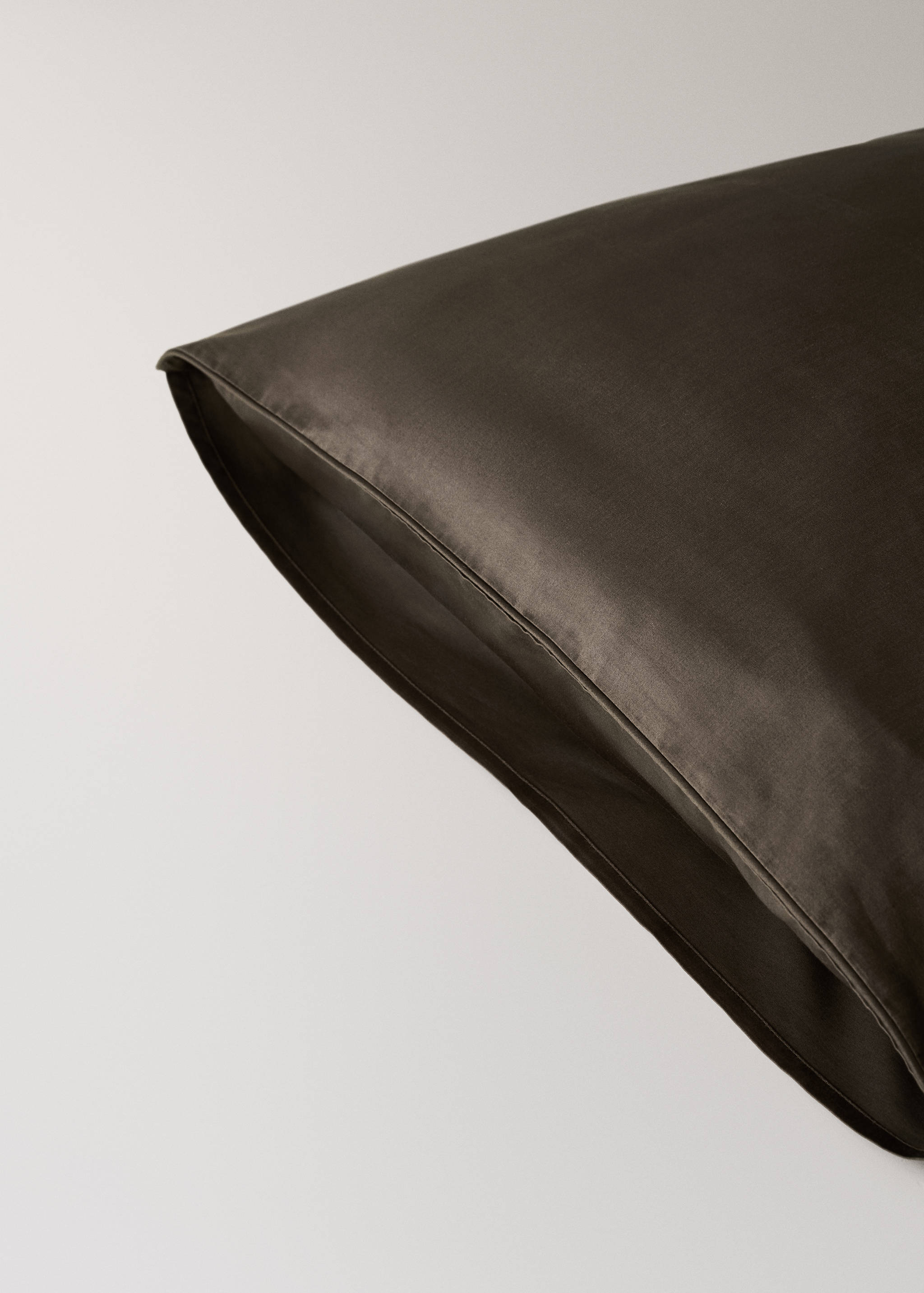 Dark brown pillowcase detail showing the corner seam and smooth fabric.