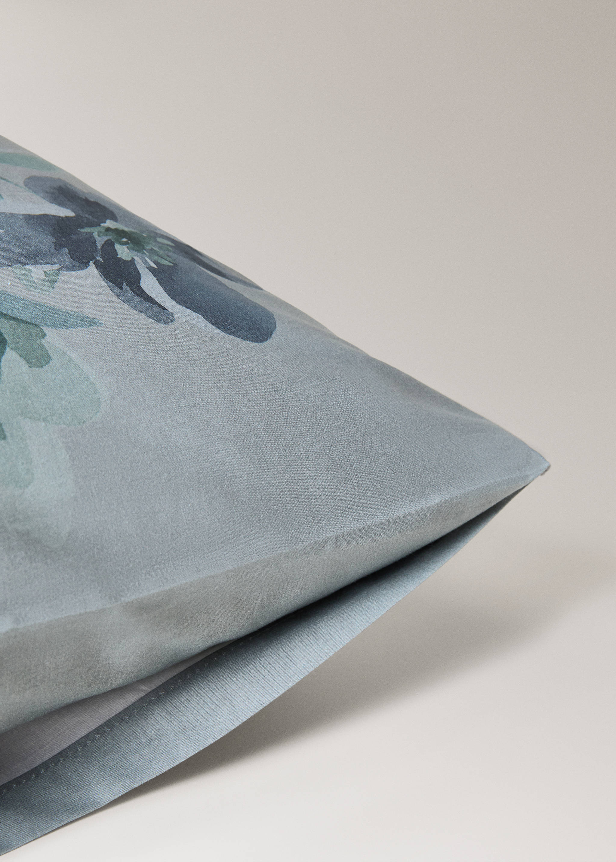 Close-up of a greyish-blue pillowcase with a floral watercolour pattern.