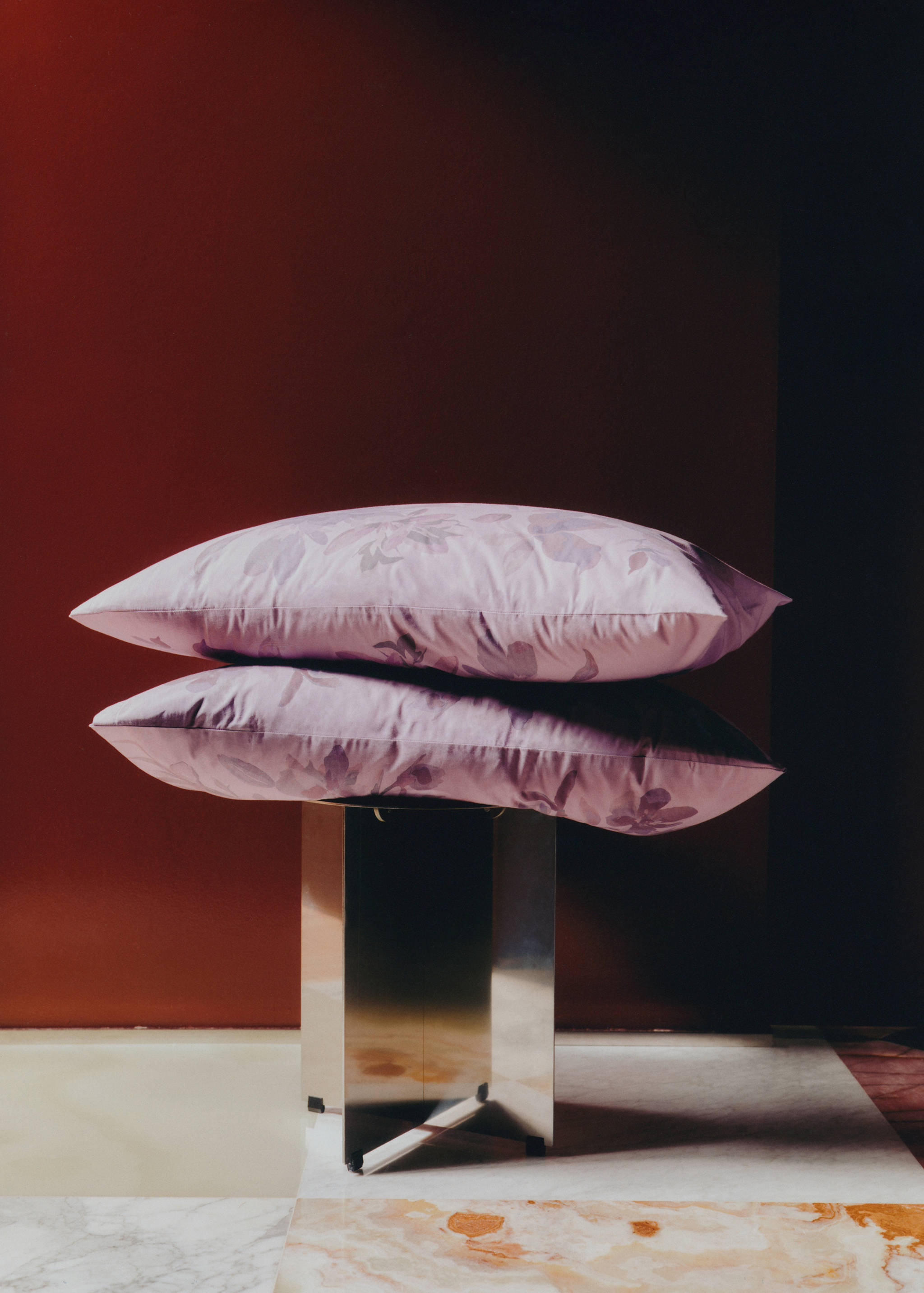 Set of two pale purple floral pillowcases stacked on a metallic stool.