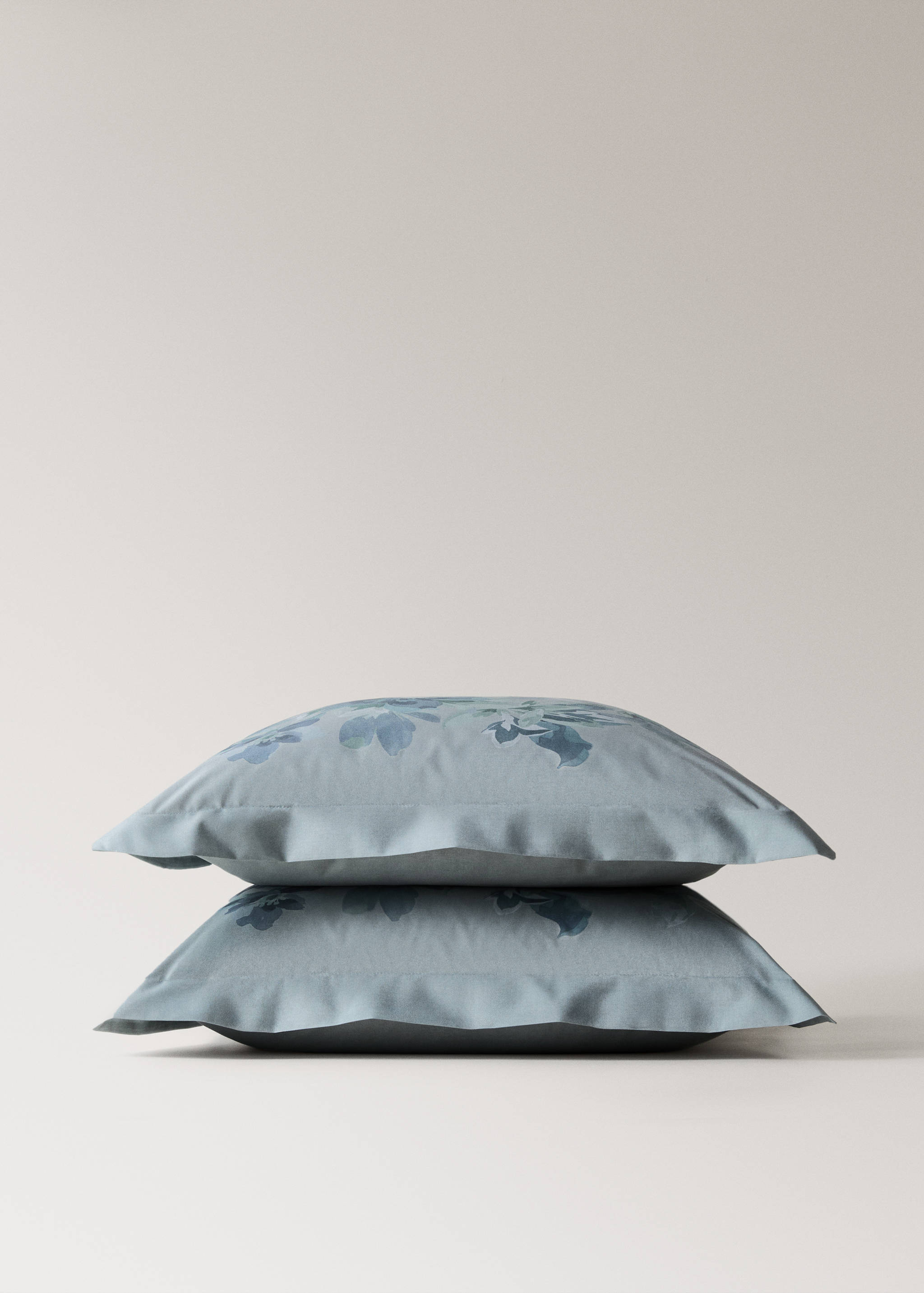 Blue-grey floral pillowcase with a flanged border, shown in a stack.