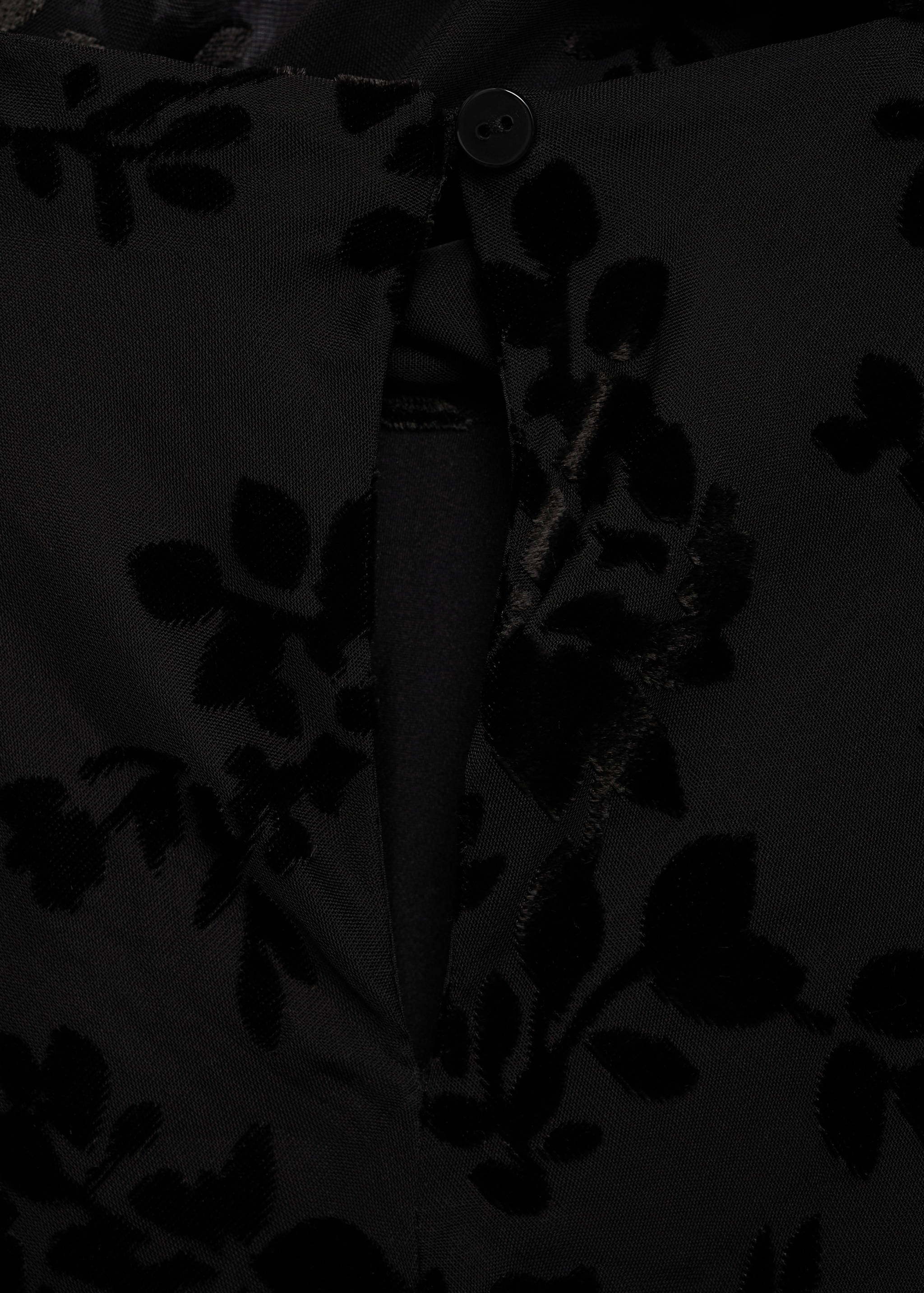 Black dress back neck detail with a keyhole button closure and floral burnout pattern.