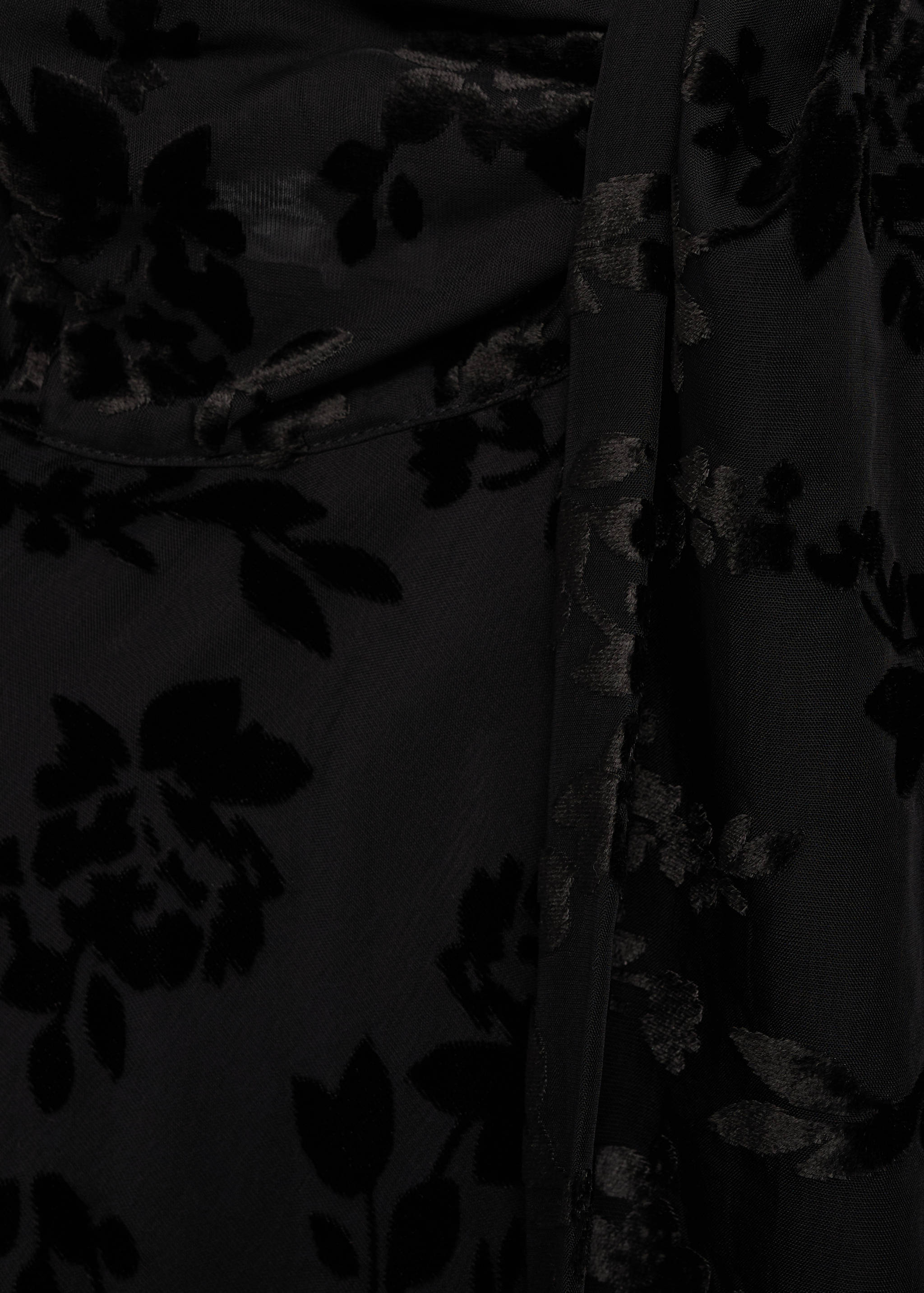 Close-up of black dress fabric featuring a velvety floral burnout pattern.