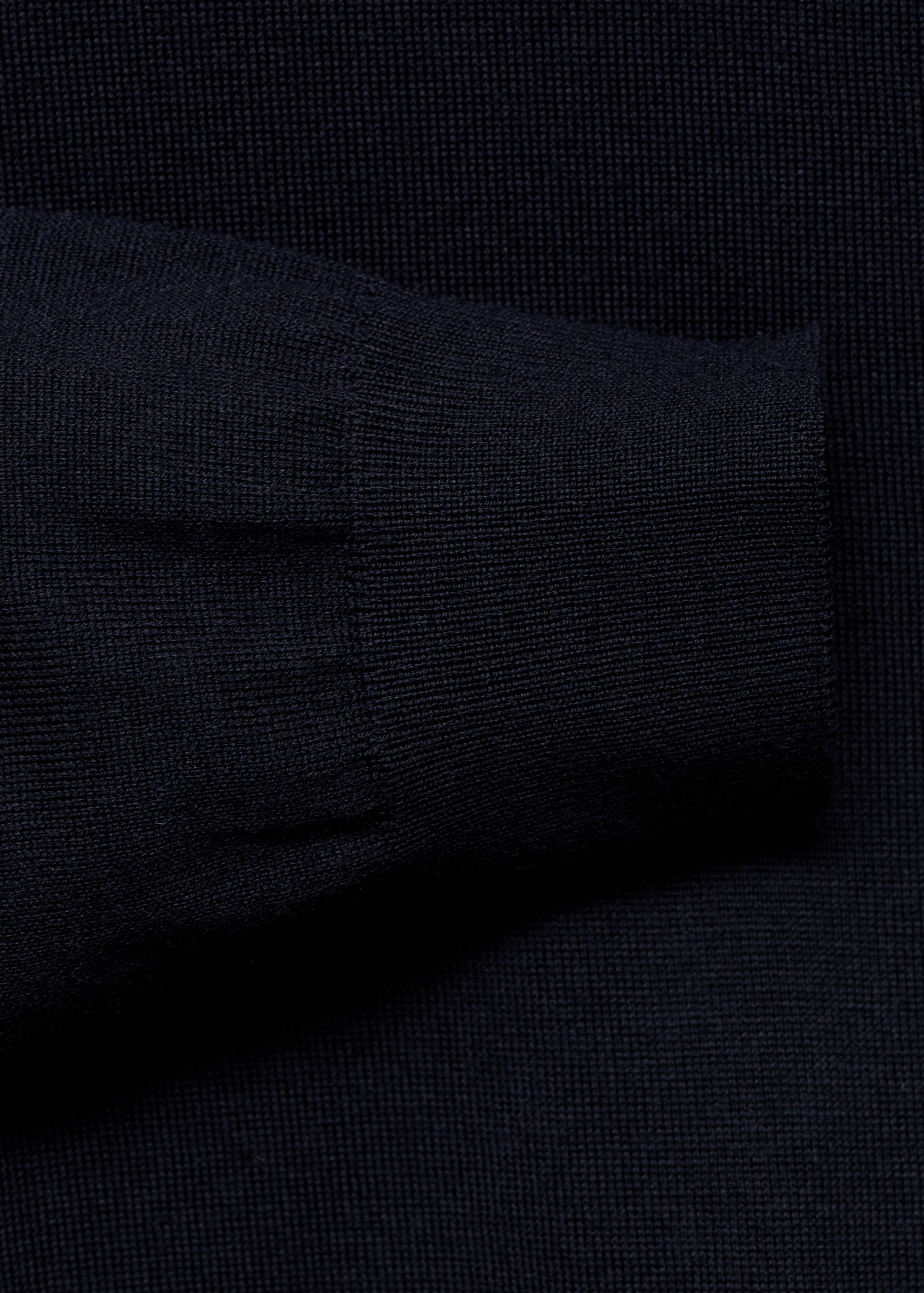 Close-up of the ribbed cuff and knit texture of a navy blue jersey.
