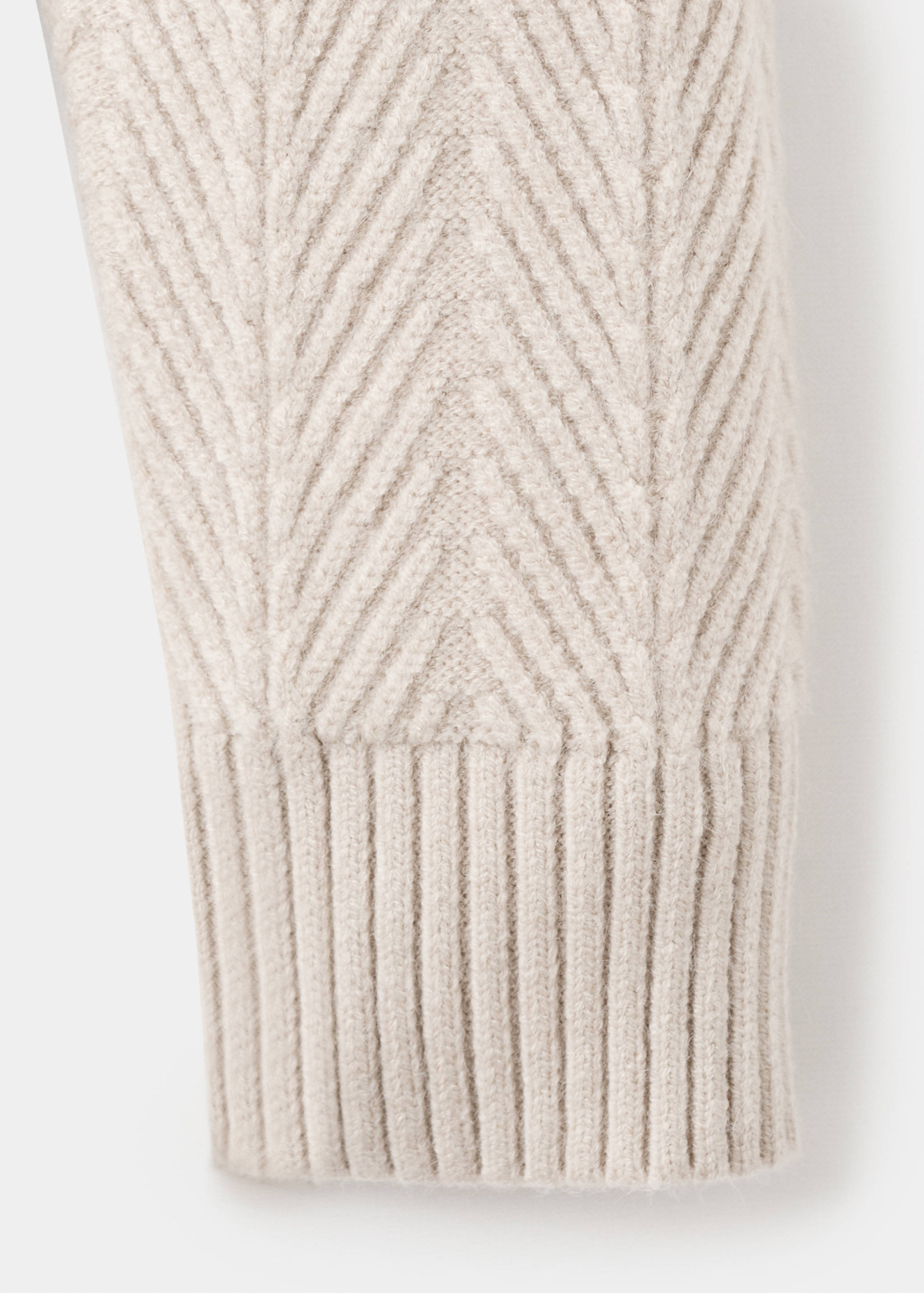 Beige jersey sleeve close-up with chevron knit and ribbed cuff.