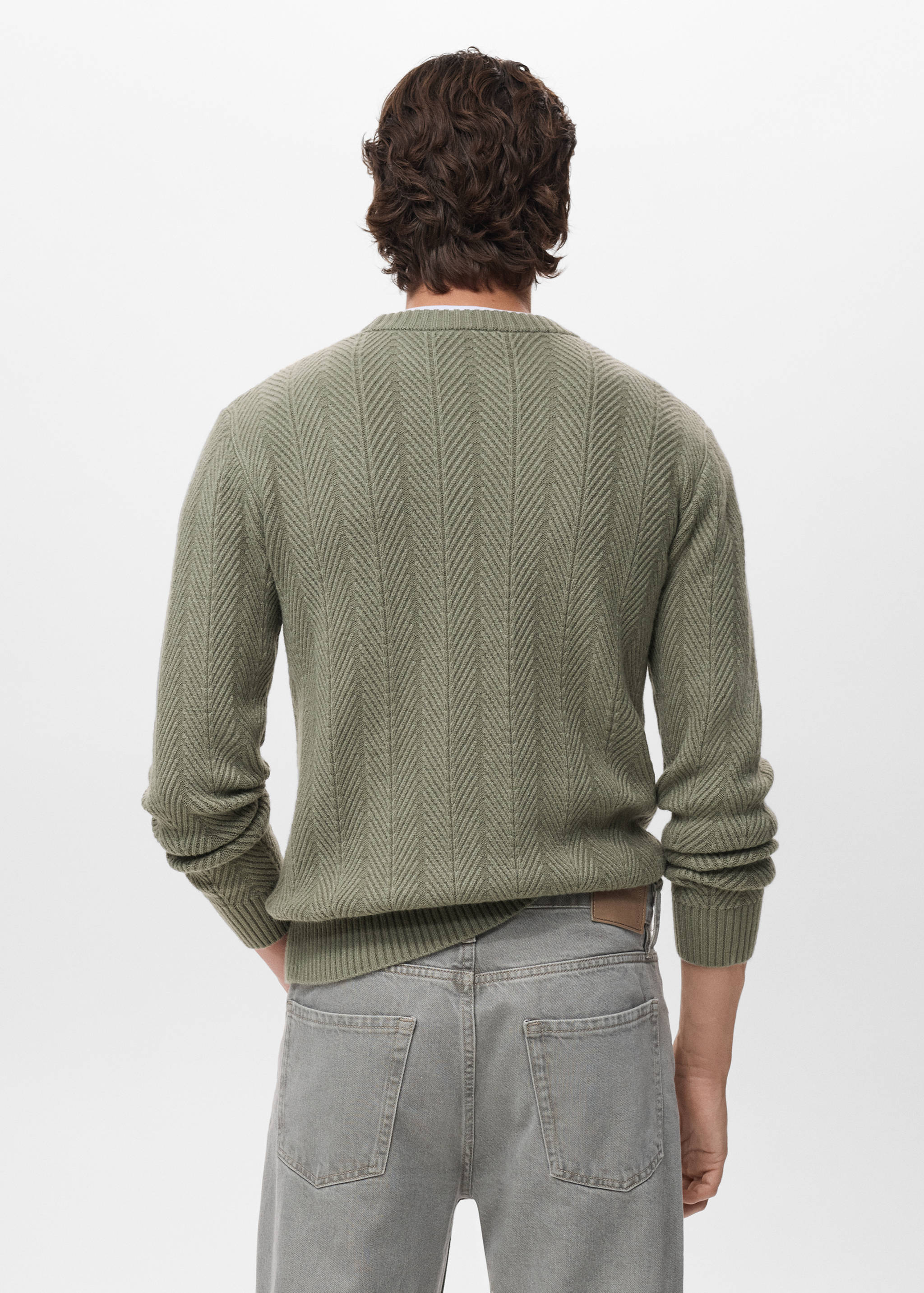 Back view of a green knitted jersey with a textured chevron pattern and ribbed crew neck.