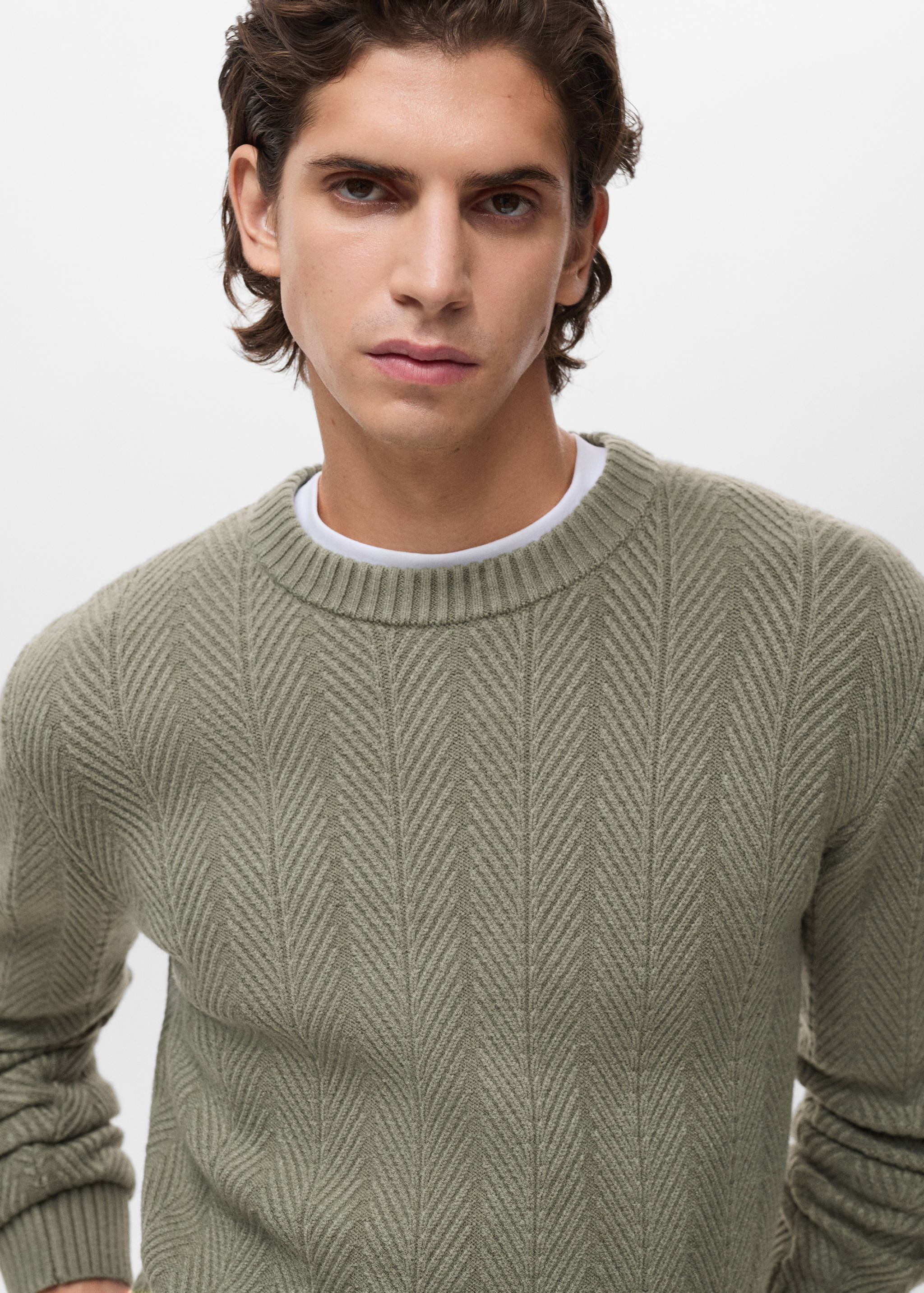 Olive green knitted jersey with chevron pattern and round neckline.