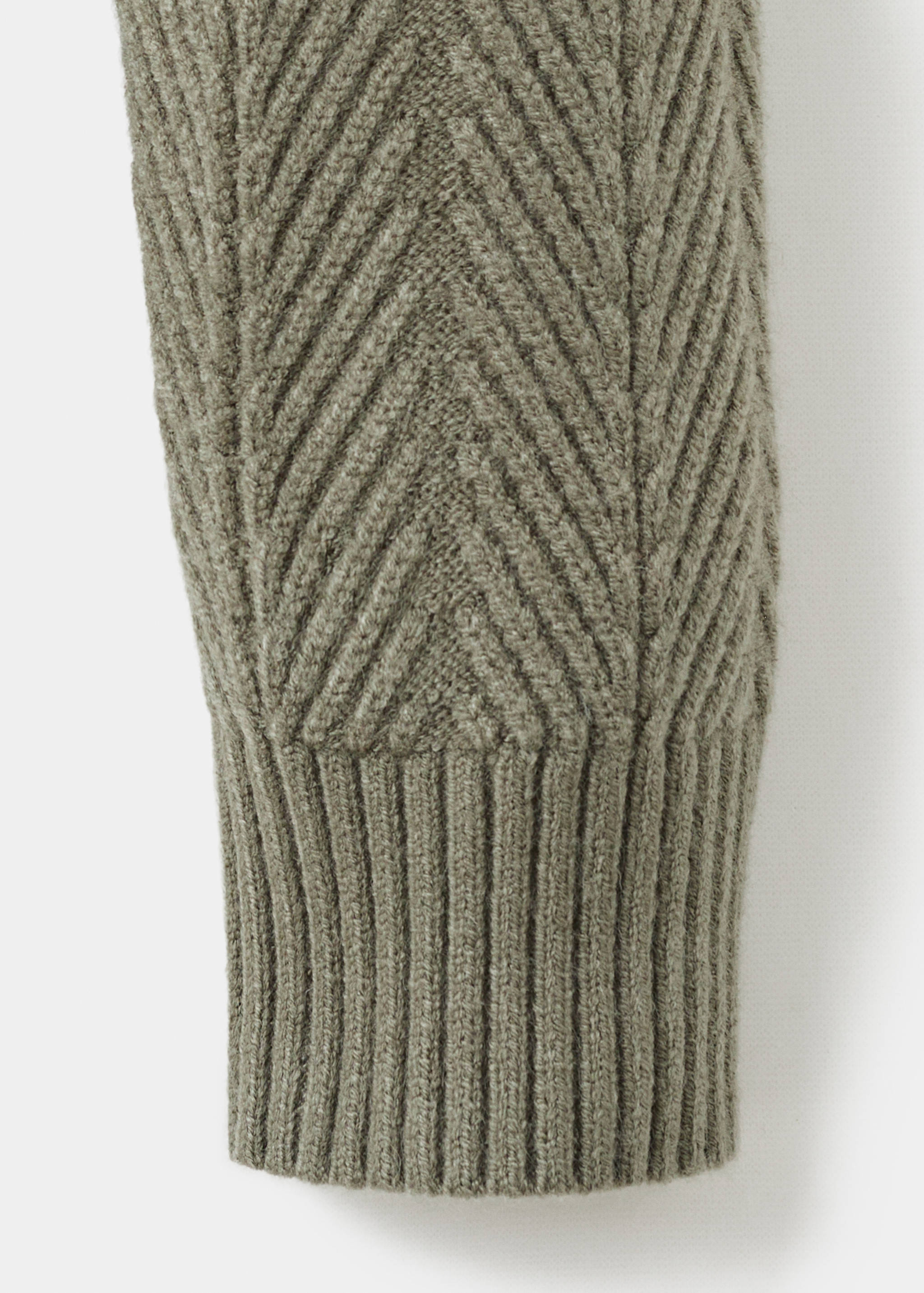 Close-up of an olive green jersey sleeve with chevron knit and ribbed cuff.