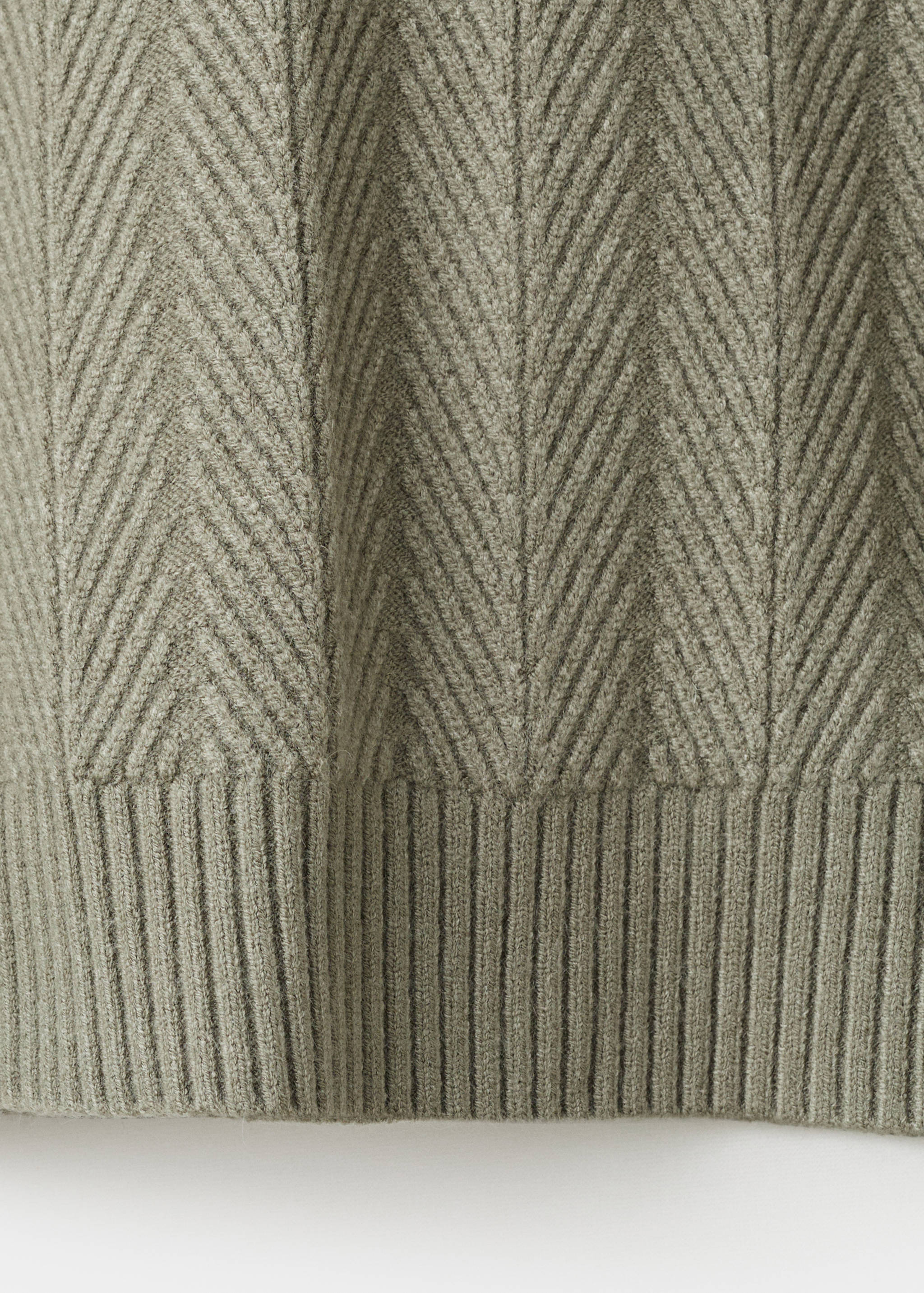 Green knit jersey fabric detail with a chevron pattern and ribbed hem.