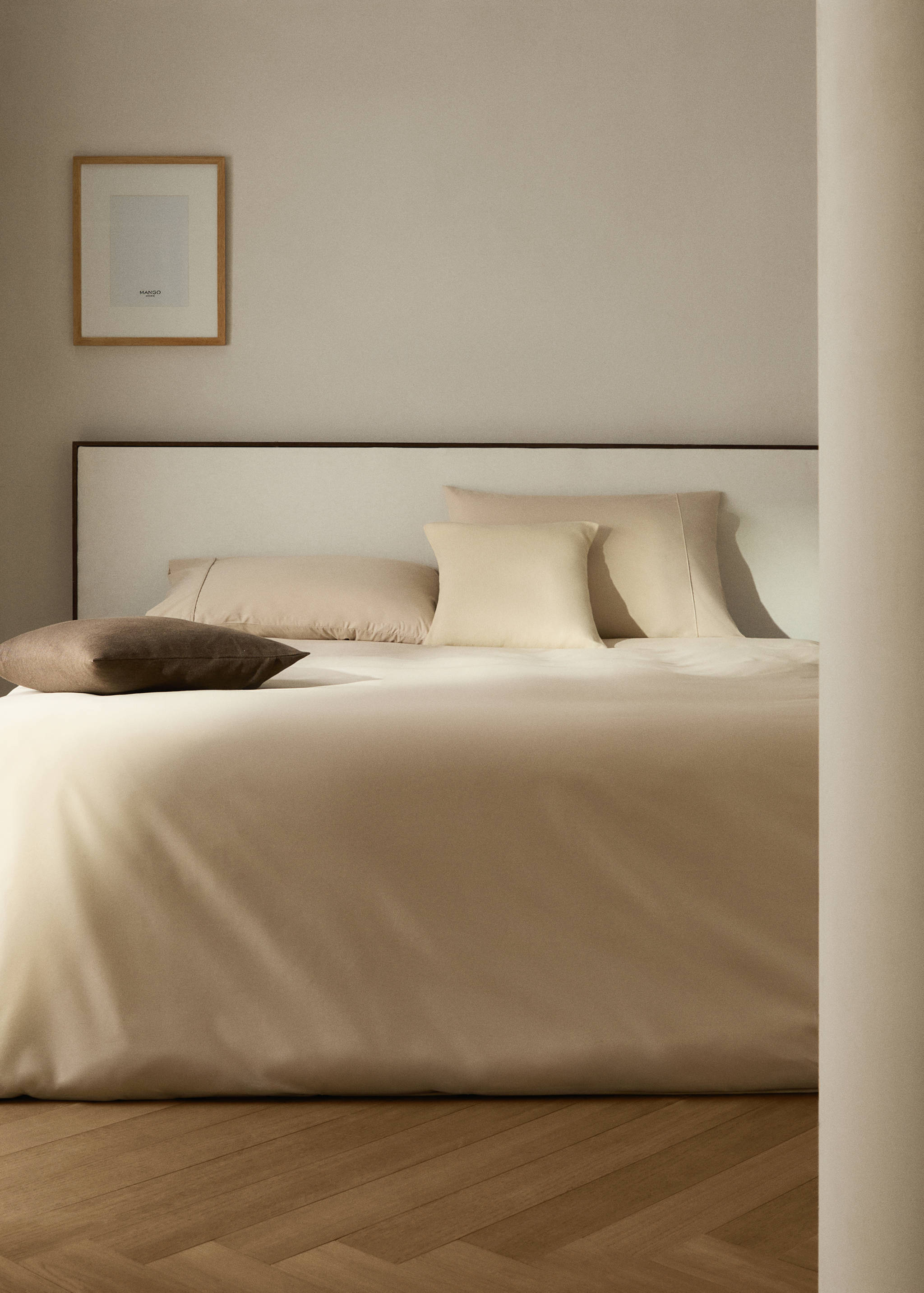 Beige duvet cover on a made bed with matching pillows and cushions.