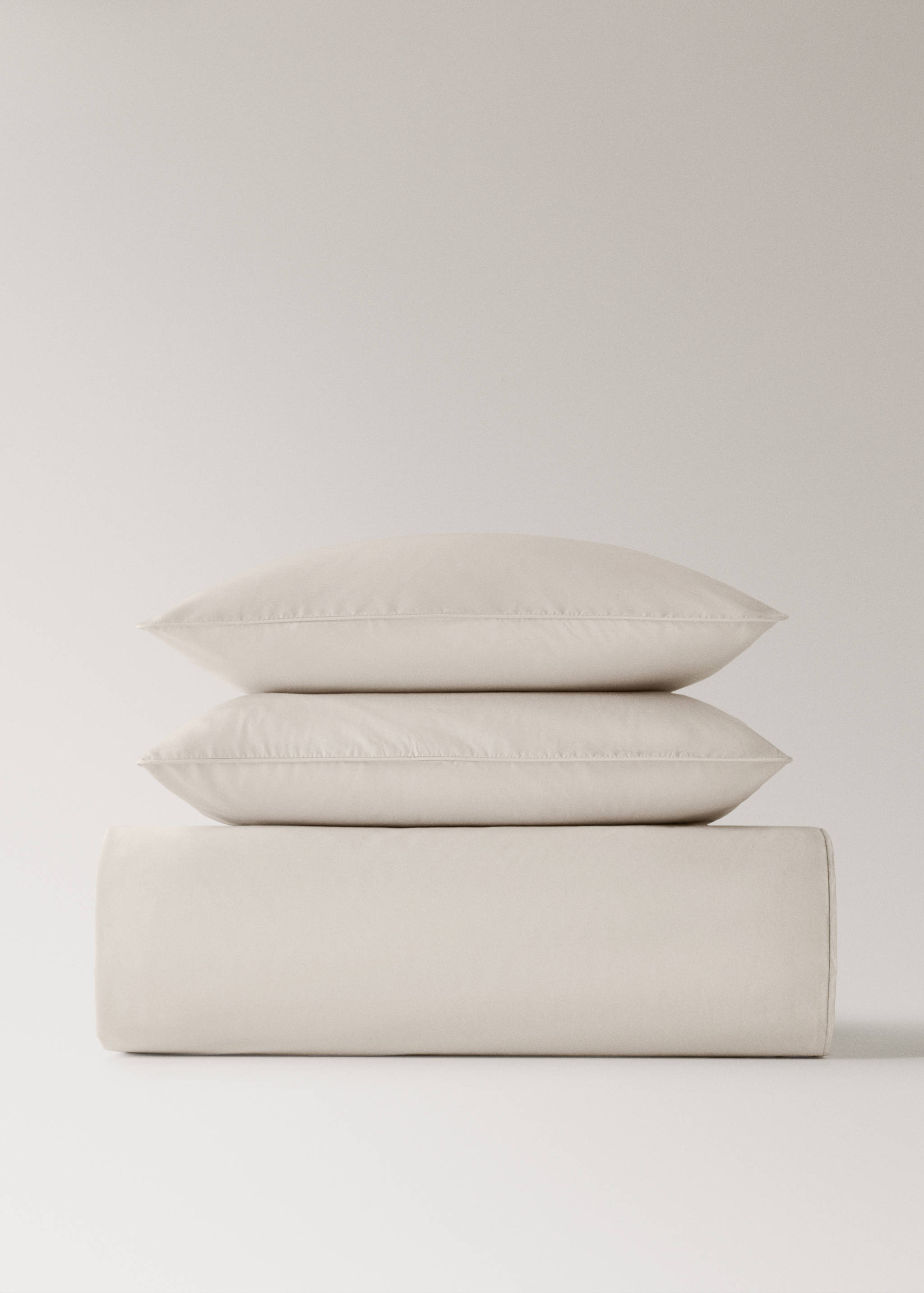 Neutral beige duvet cover neatly folded in a still-life setup with matching pillows.