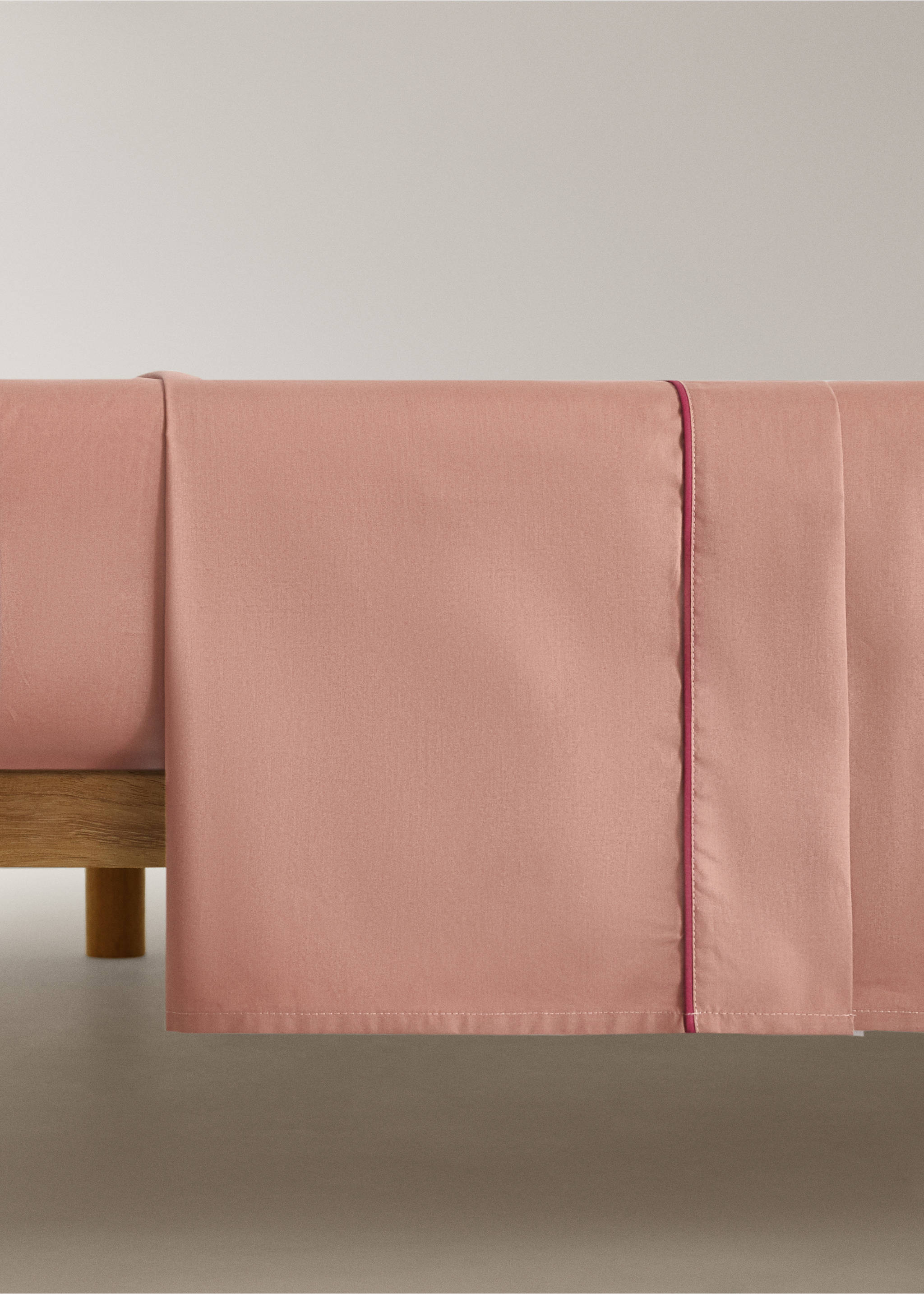 Pink flat sheet with contrasting dark pink piped trim on a bed., Brown. Ref: 17021586-00.