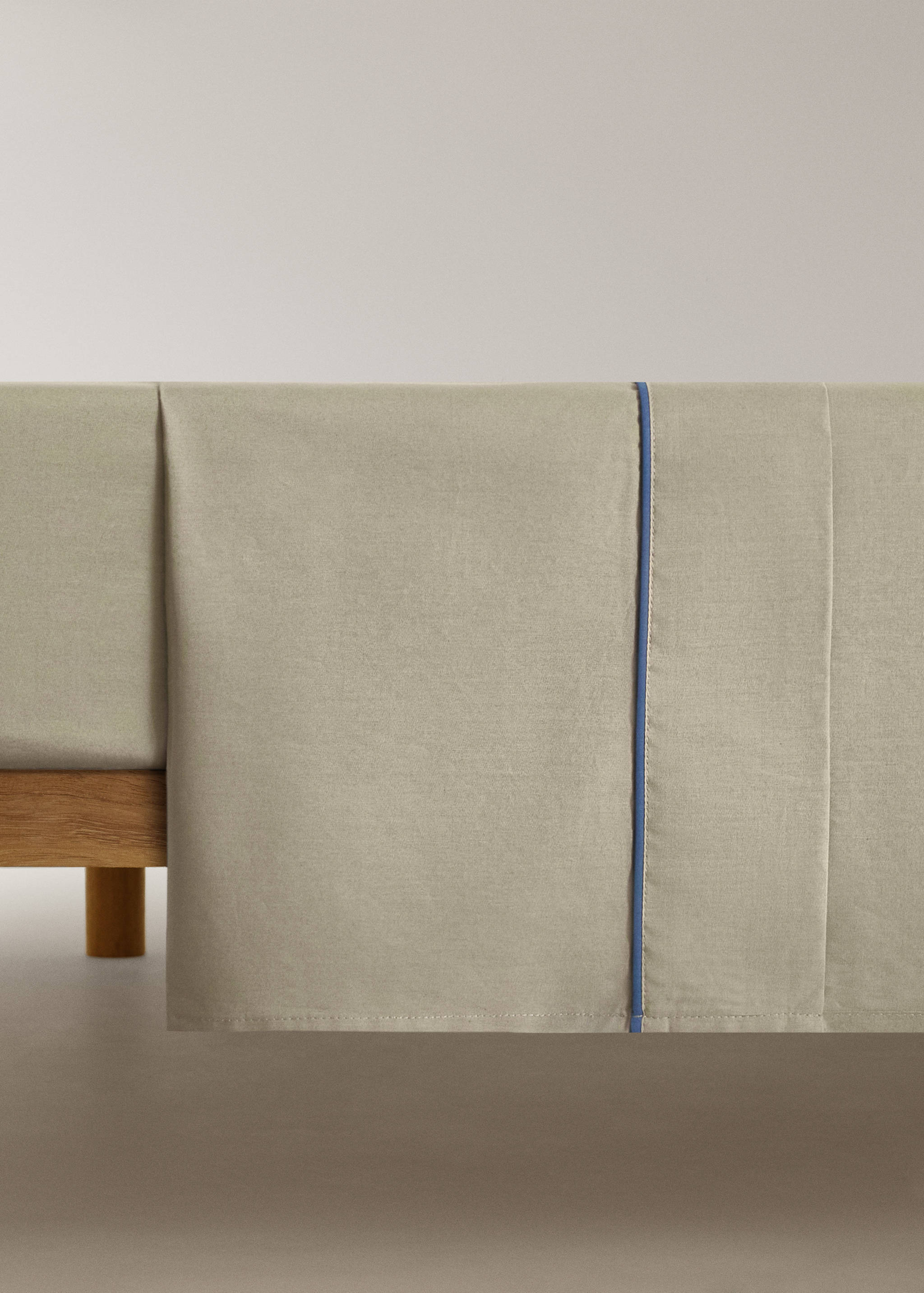 Beige flat sheet with thin blue piping trim.