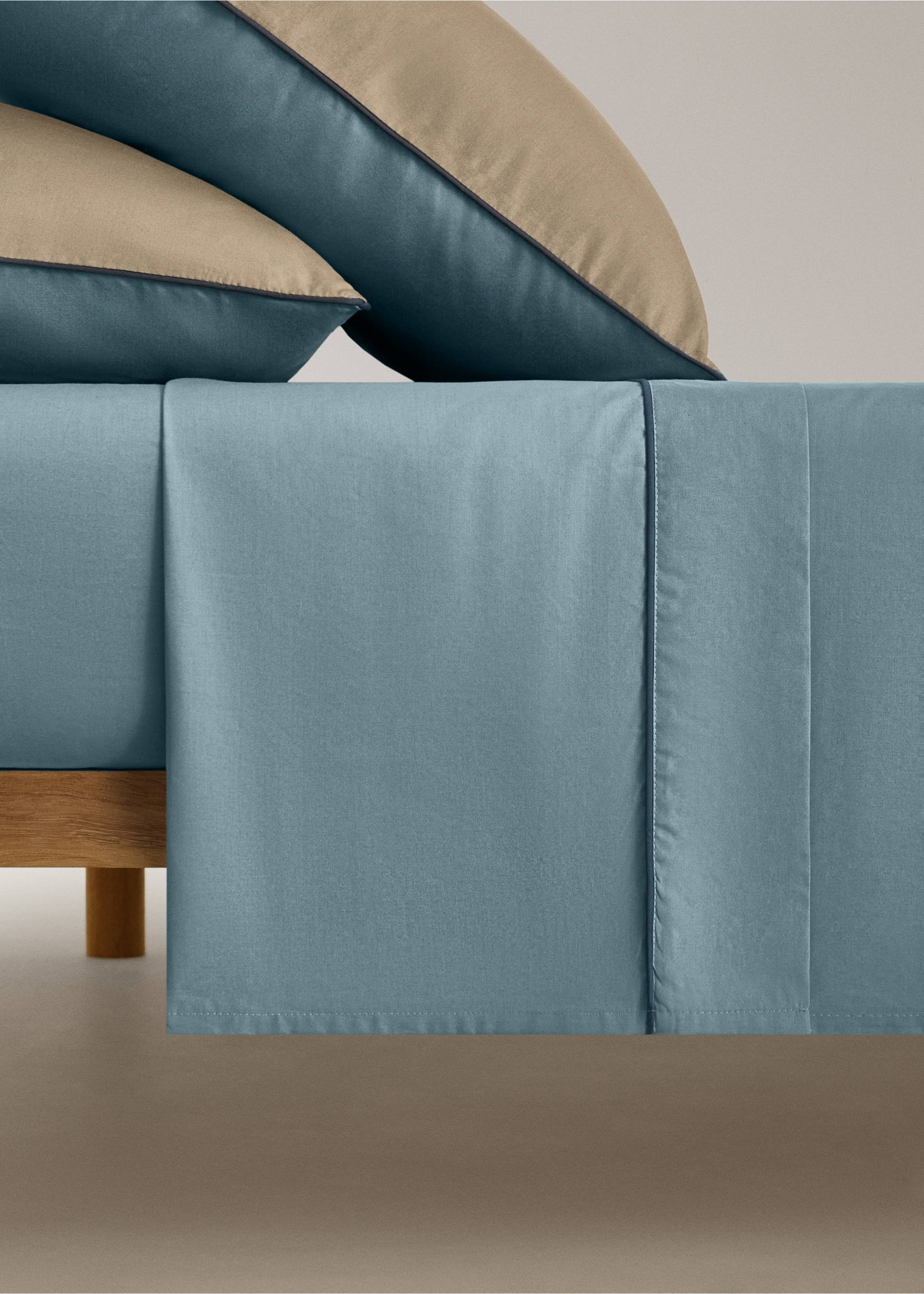 Blue flat sheet with a dark blue piped trim on a made bed., Blue. Ref: 17021586-00.