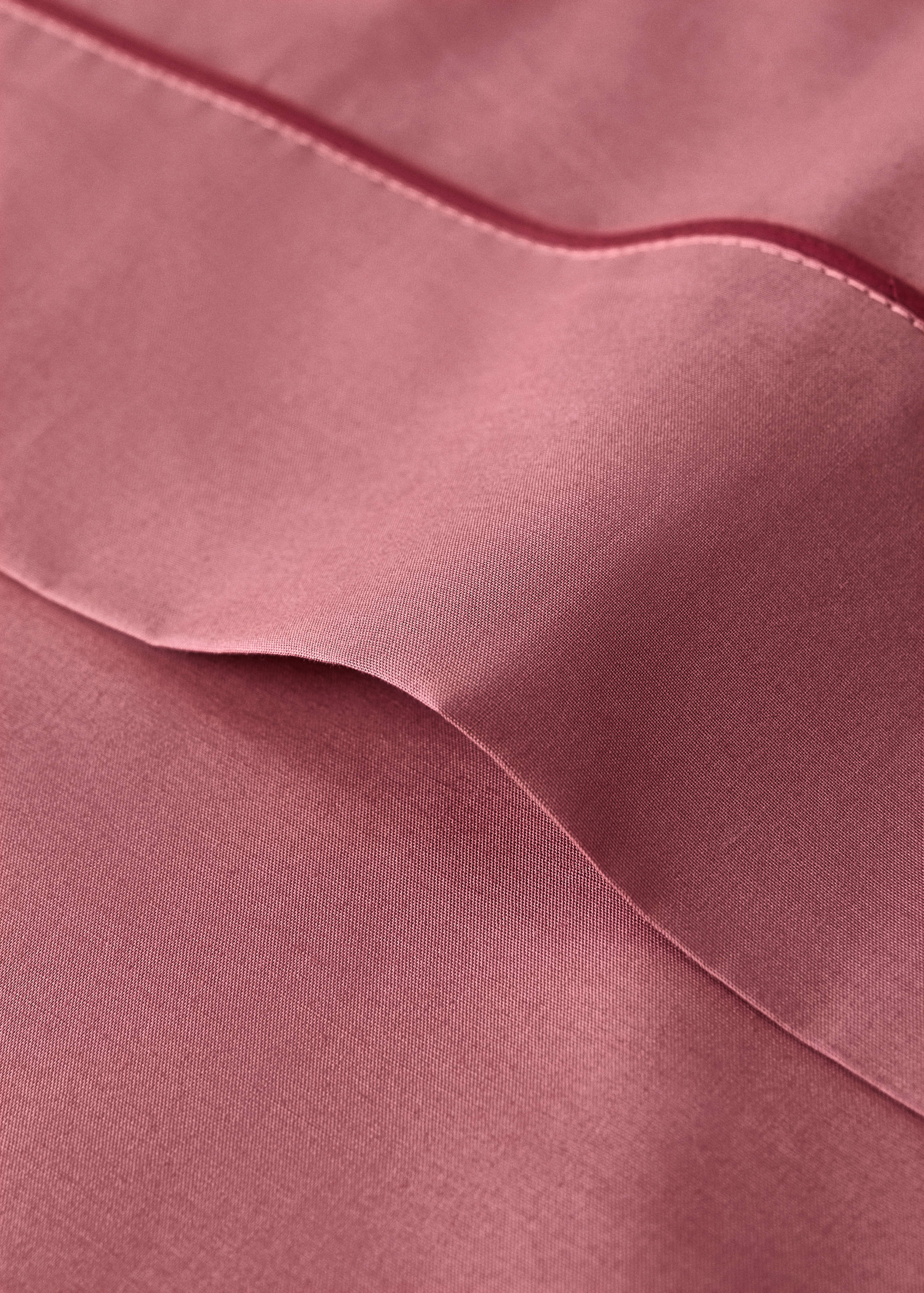 Pink flat sheet detail with a contrasting piped trim.