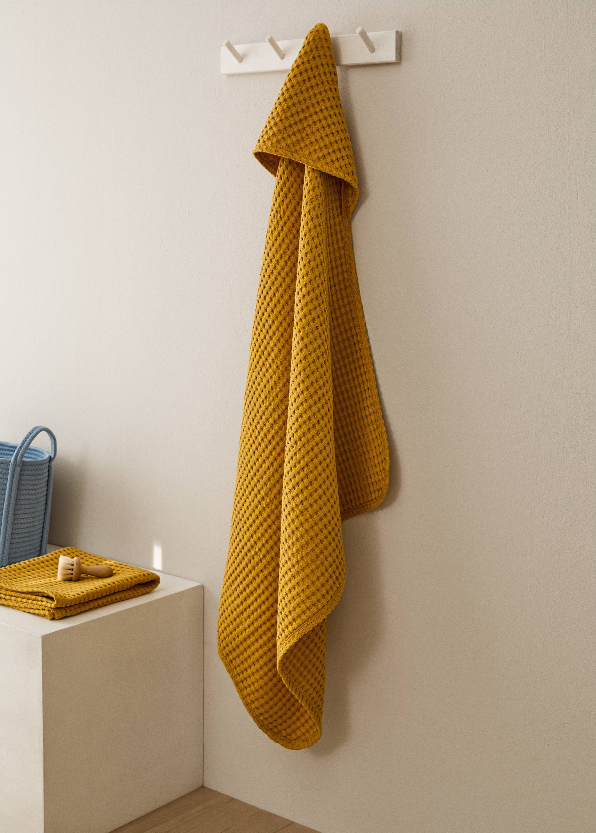 Mustard yellow waffle-weave towel hanging on a wall peg.