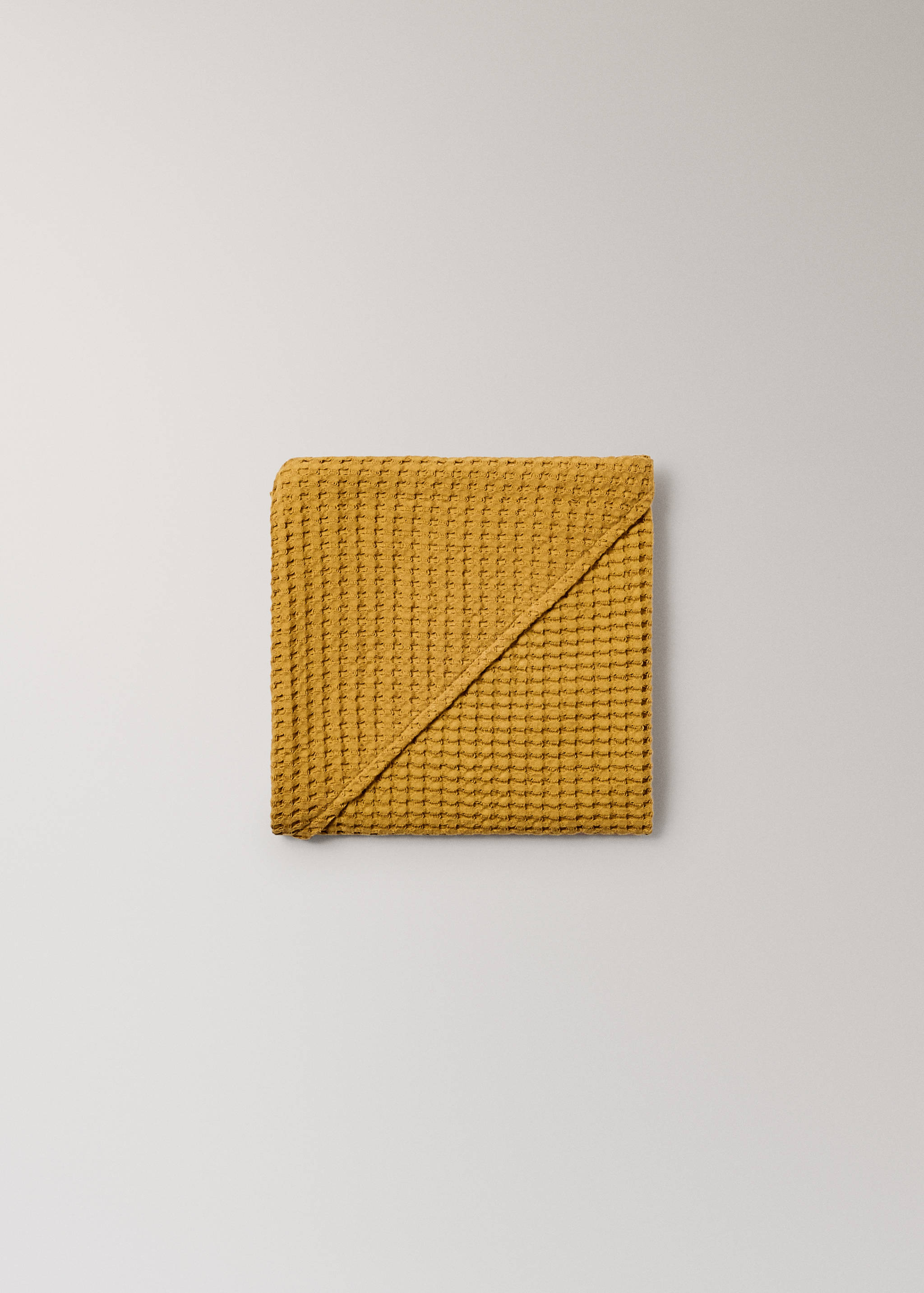 Mustard yellow waffle-weave cotton towel, folded detail view.