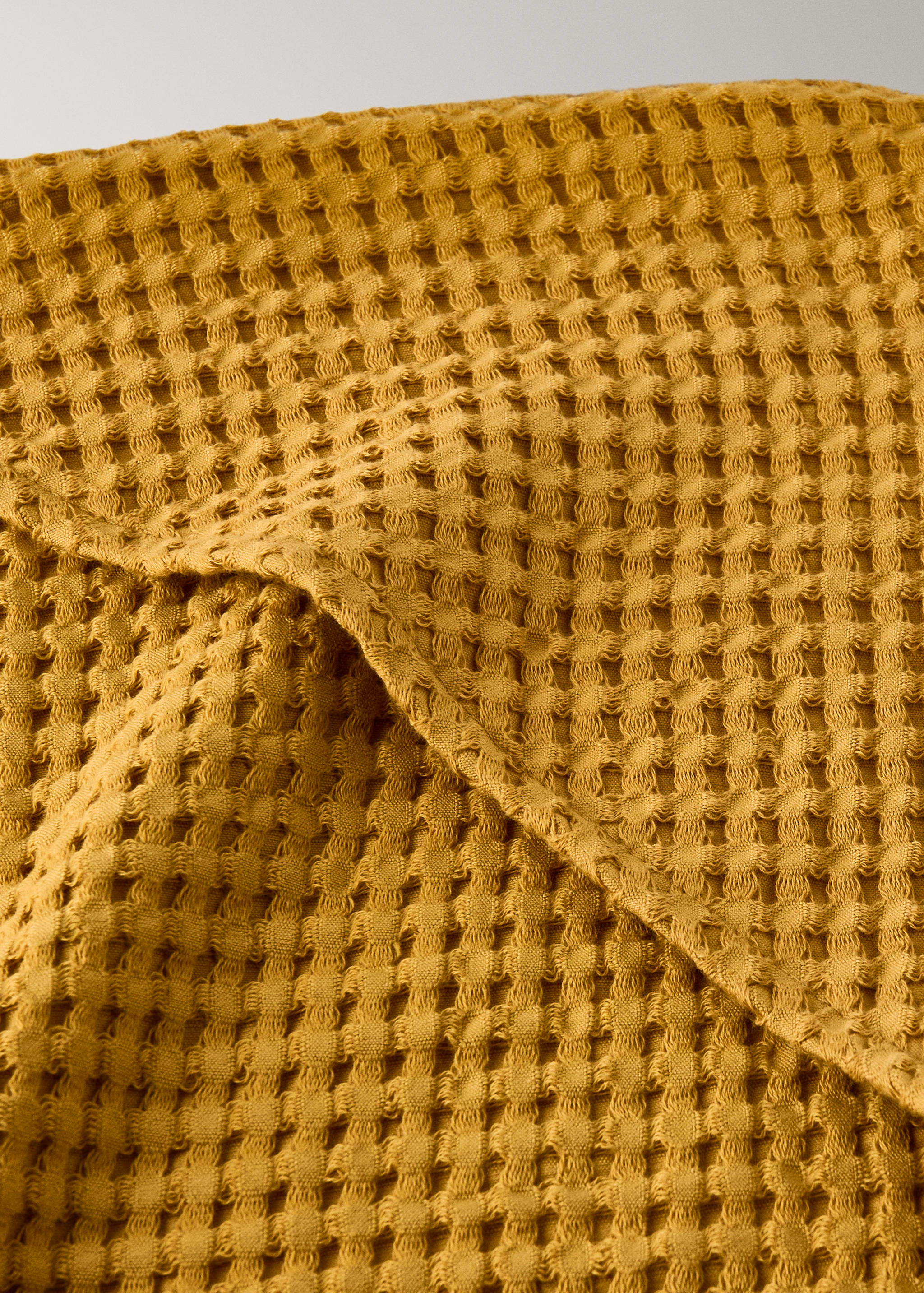 Ochre yellow waffle-weave towel close-up.